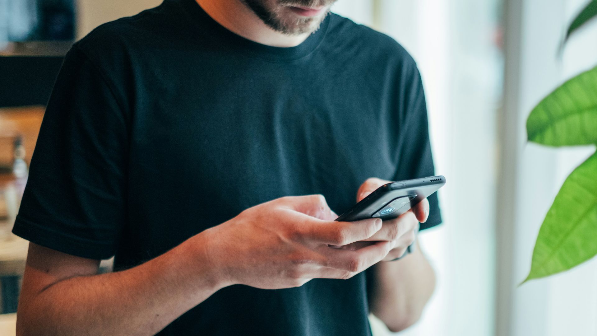 man in black crew-neck top using smartphone