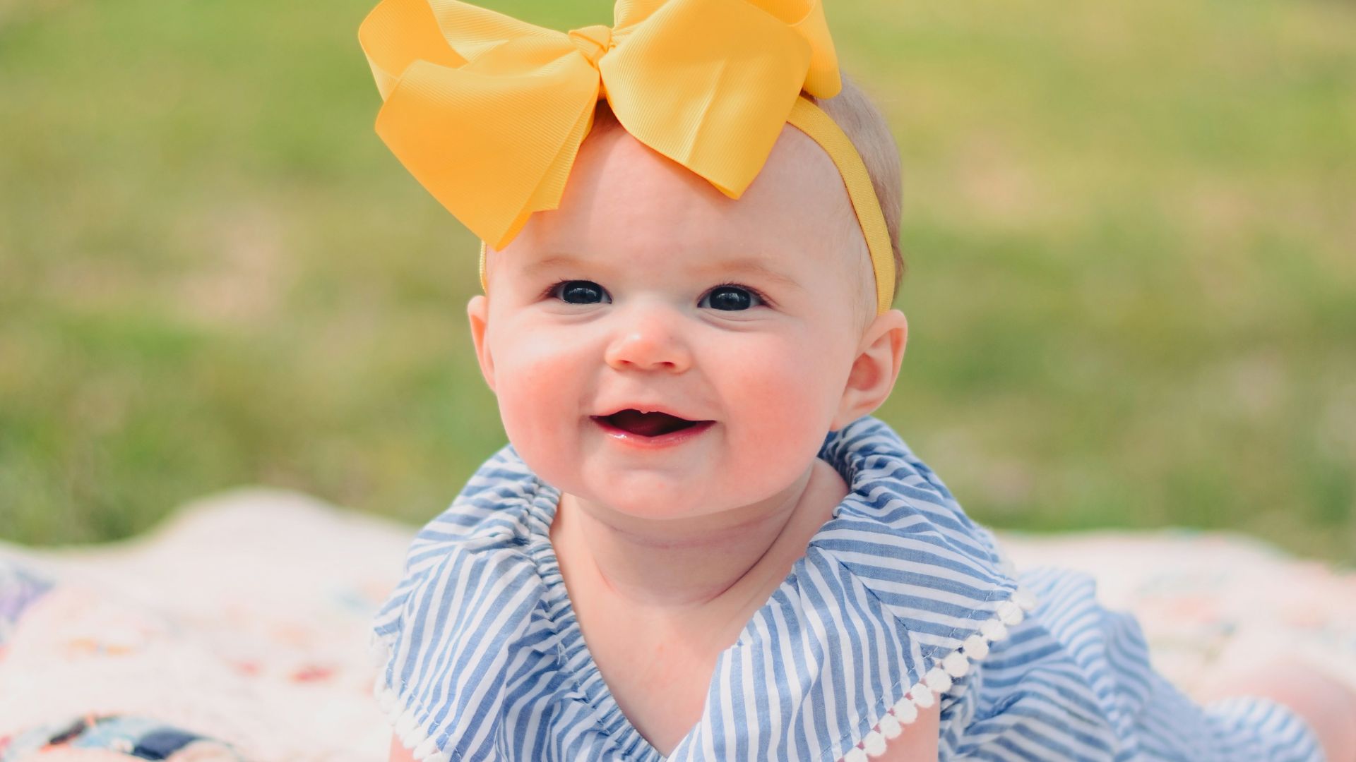 smiling baby lying forward on pink textile