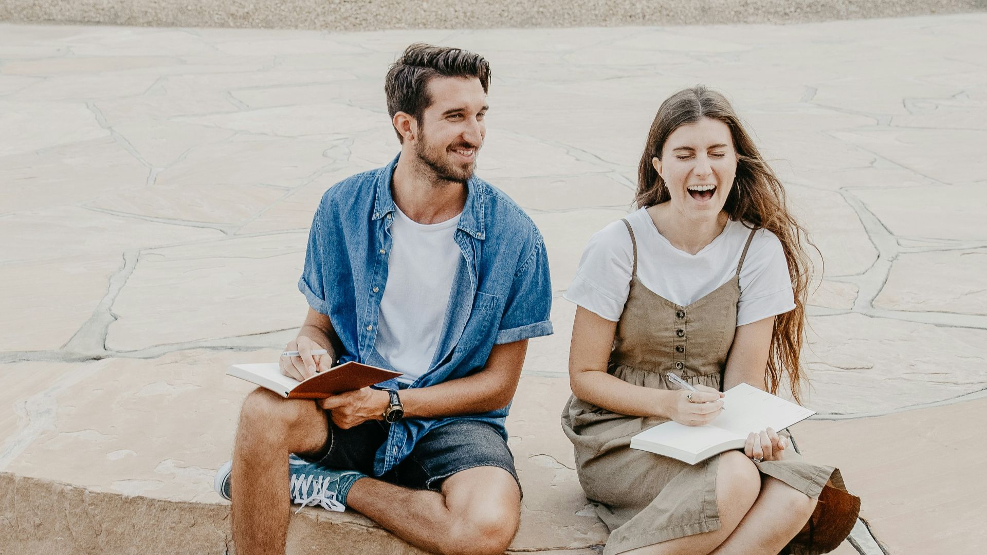 man and woman sitting side by side holding notebooks