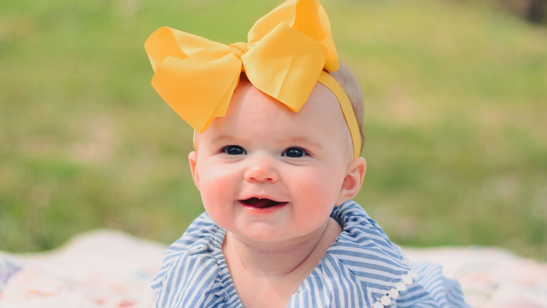 smiling baby lying forward on pink textile
