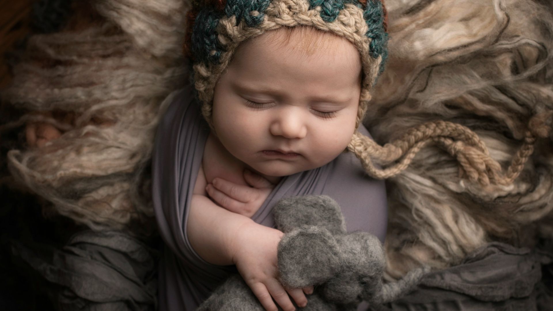 girl in grey long sleeve shirt lying on grey fur textile