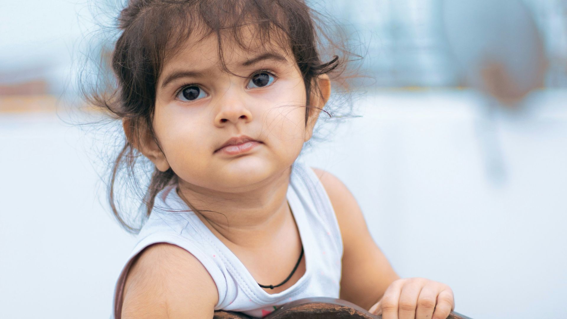 girl in white tank top sitting on brown wooden chair