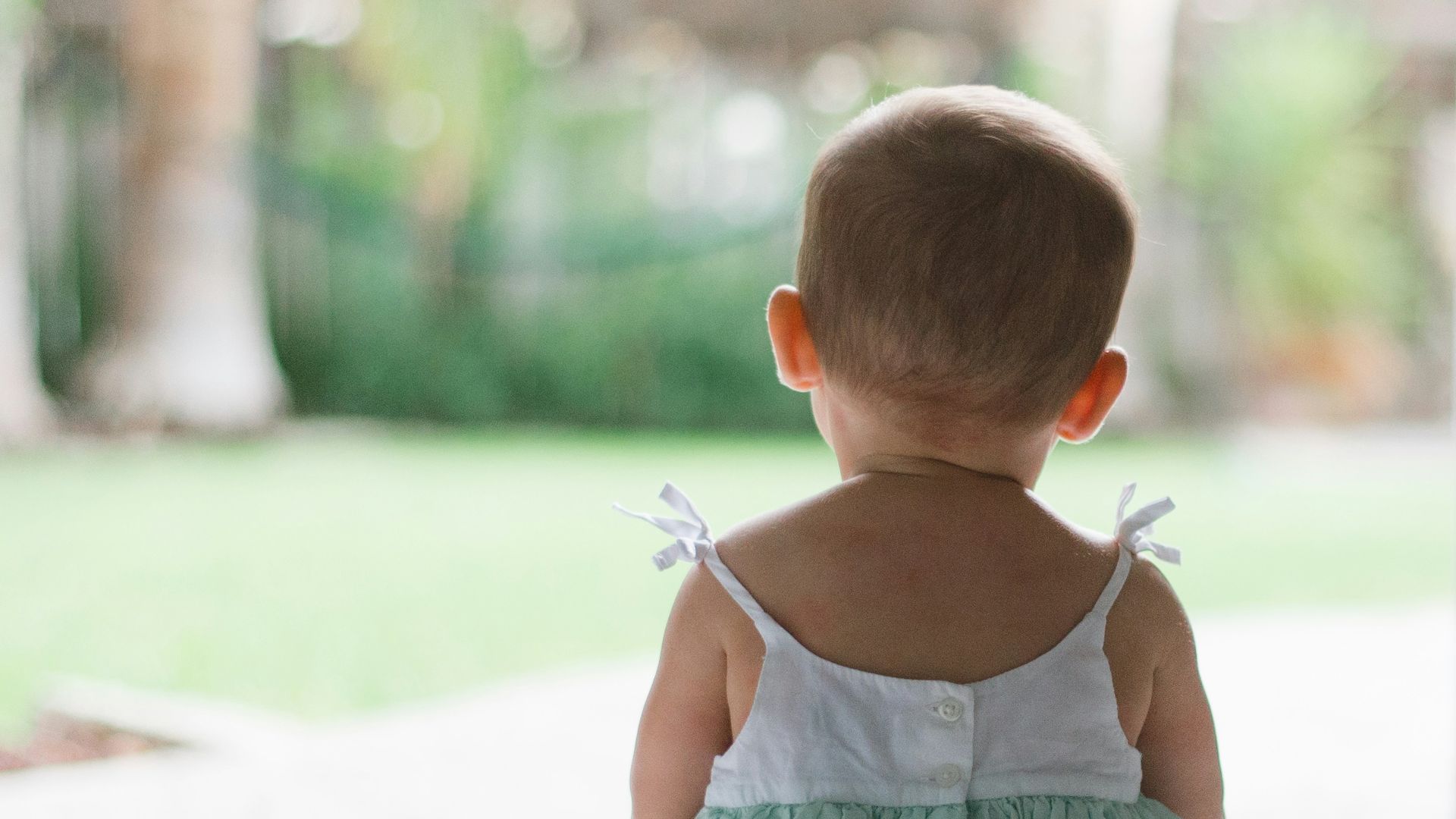 selective focus photo of toddler wearing sleeveless dress sitting on floor