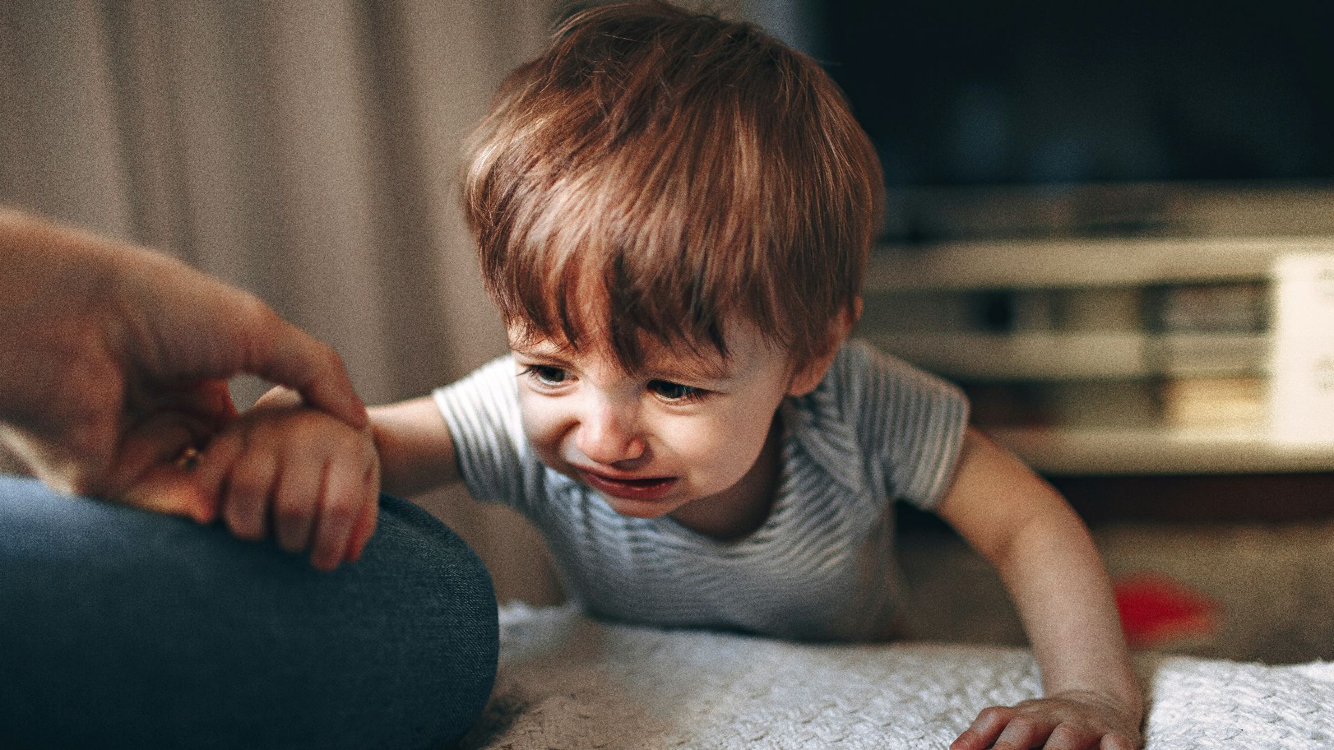 boy in gray and white striped shirt sitting on floor