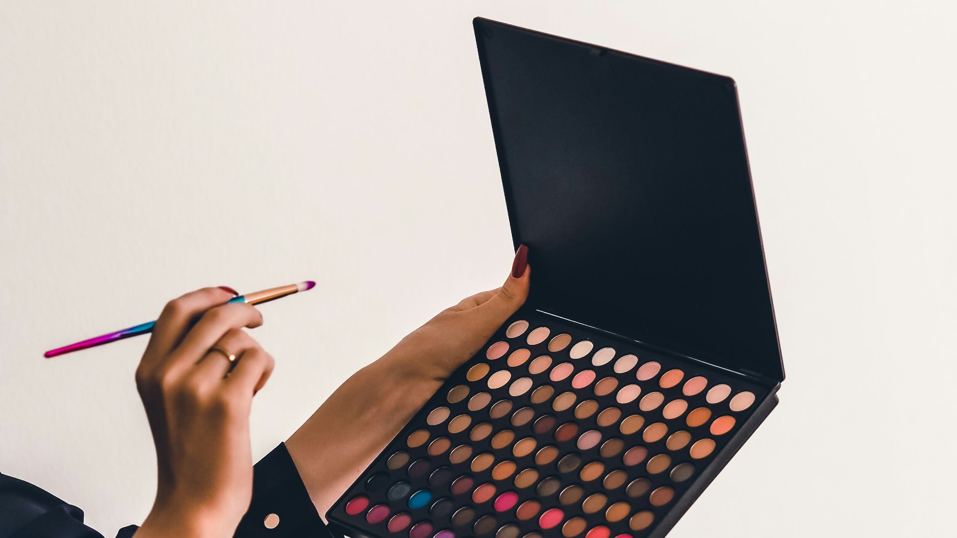 a person holding a makeup palette and a pencil