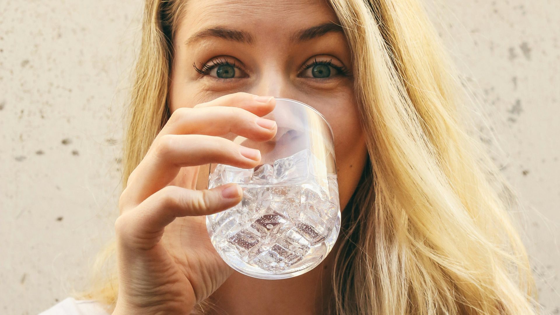 woman in white crew neck shirt drinking water