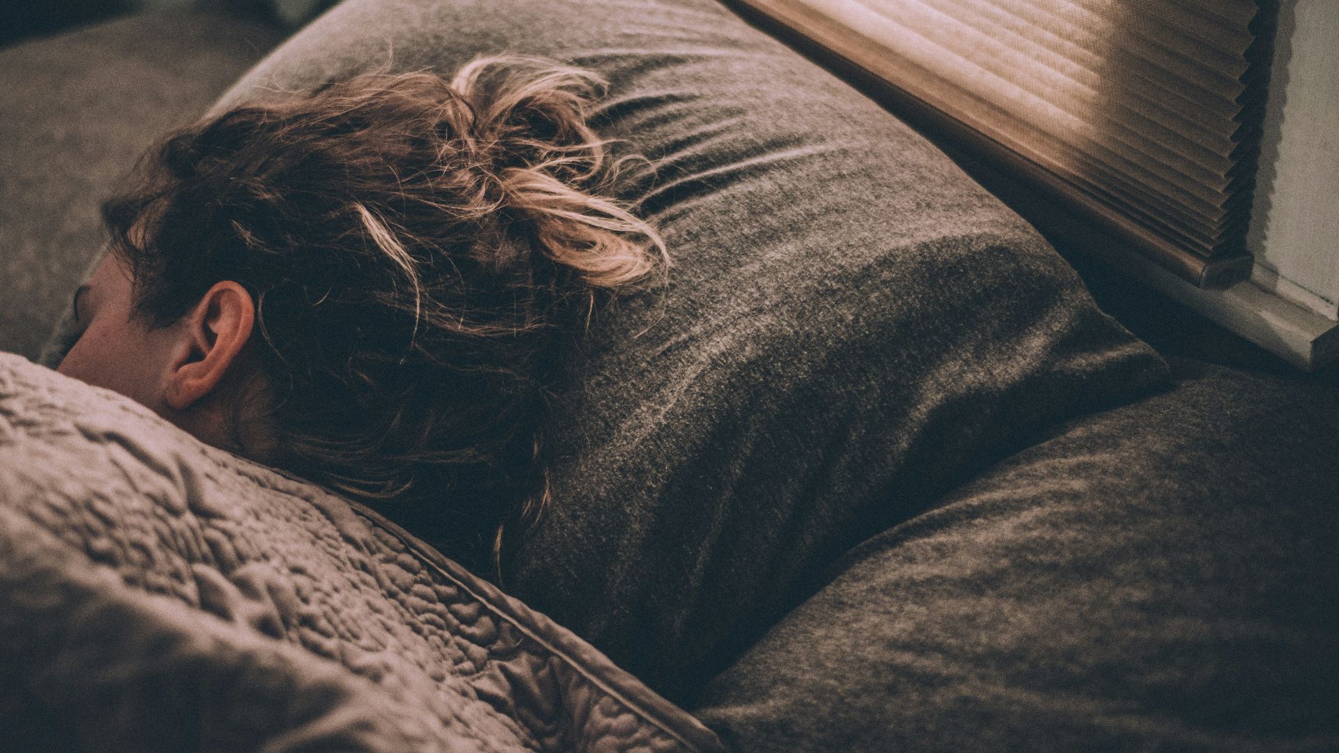 woman sleeping on bed under blankets