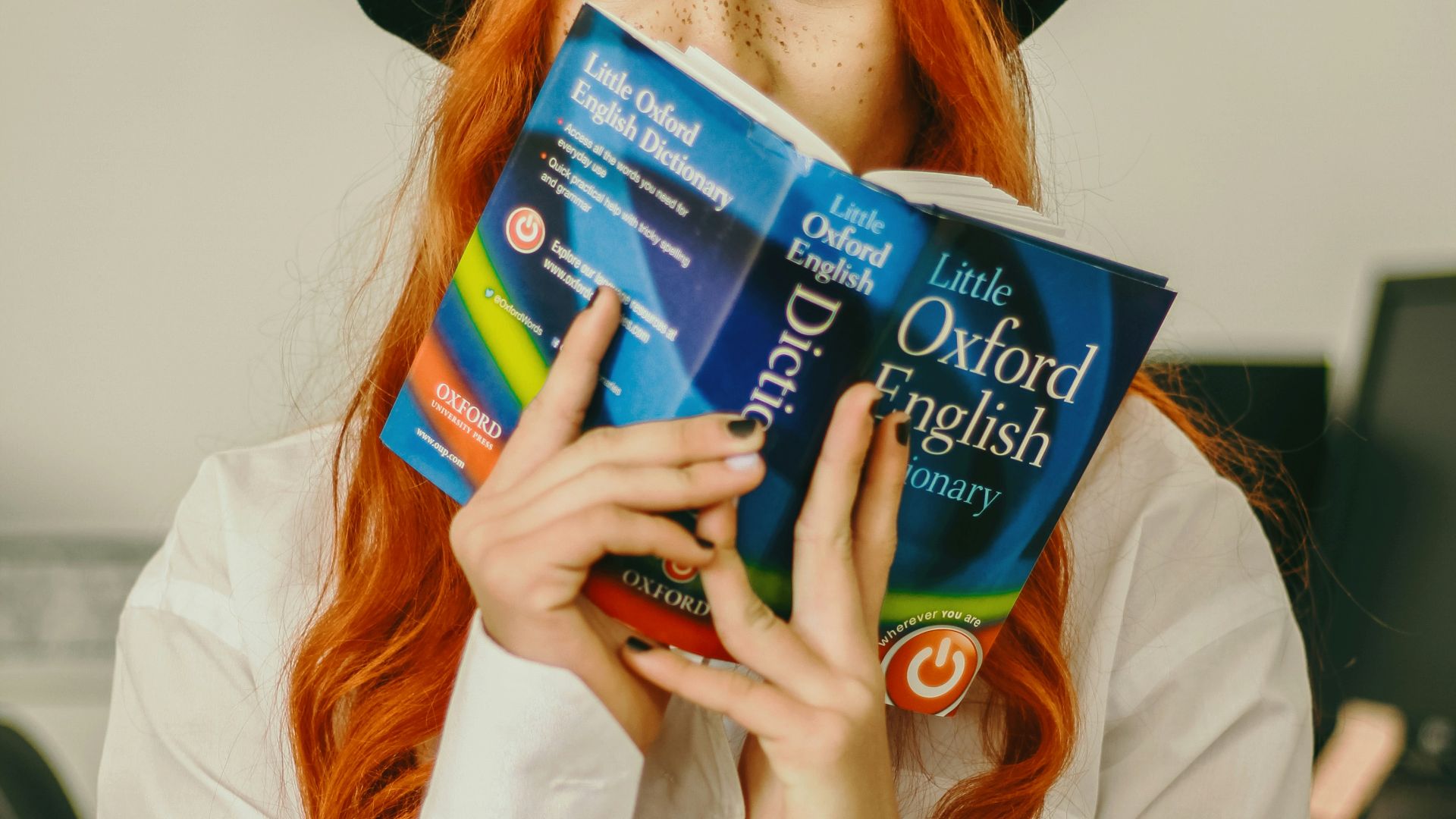 a woman with red hair is holding a book