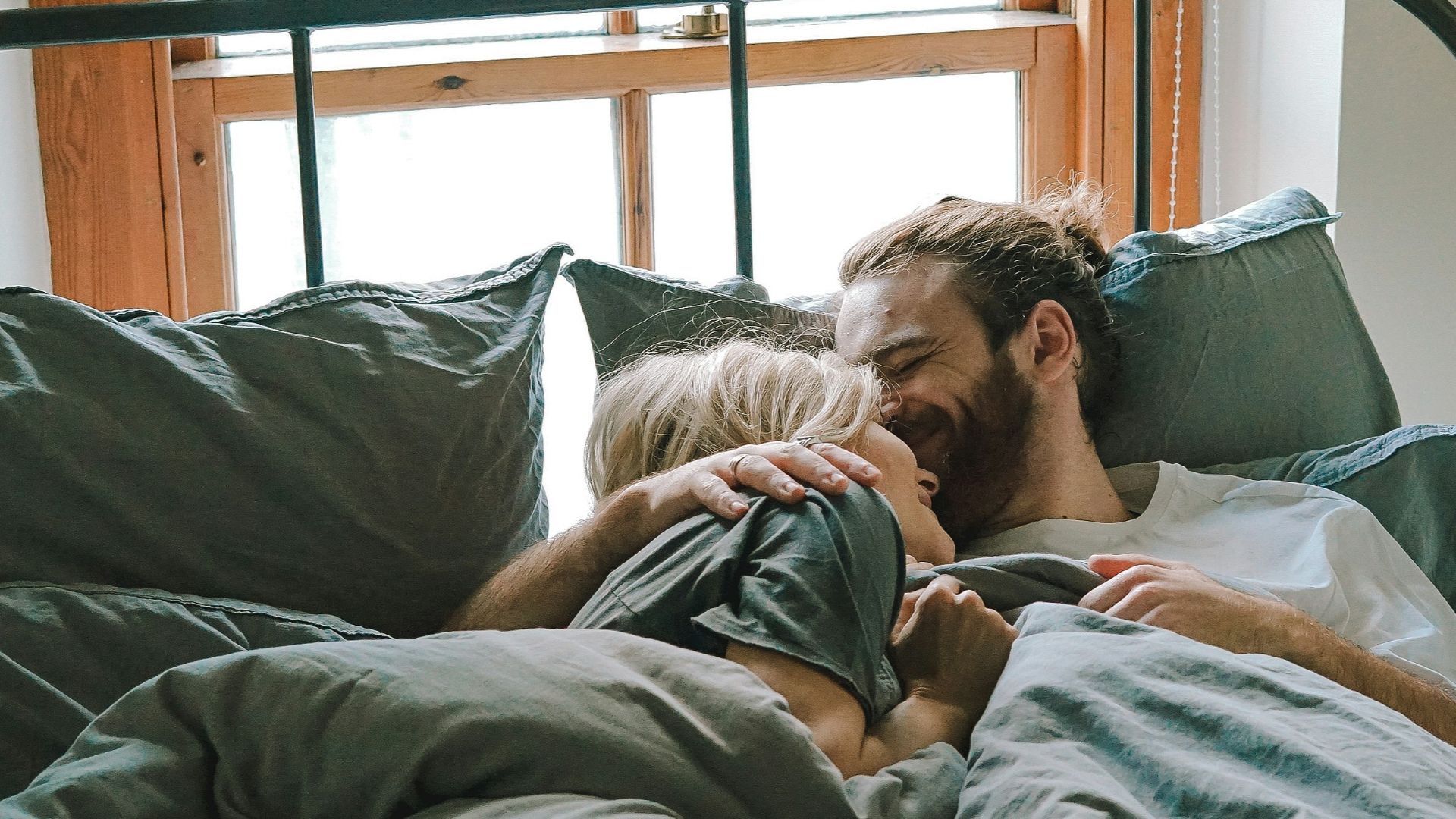 man kissing woman on her forehead