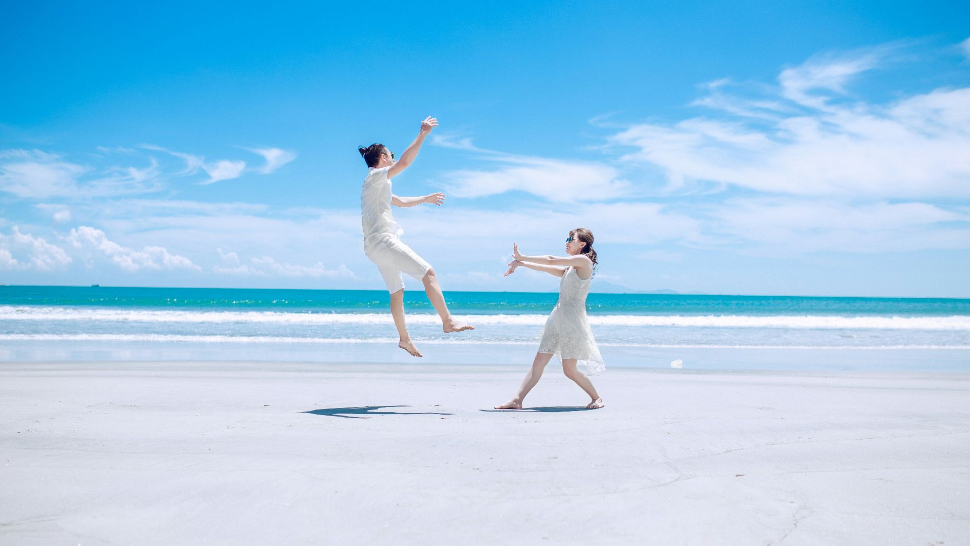 man and woman playing on white sand near seashore during daytime