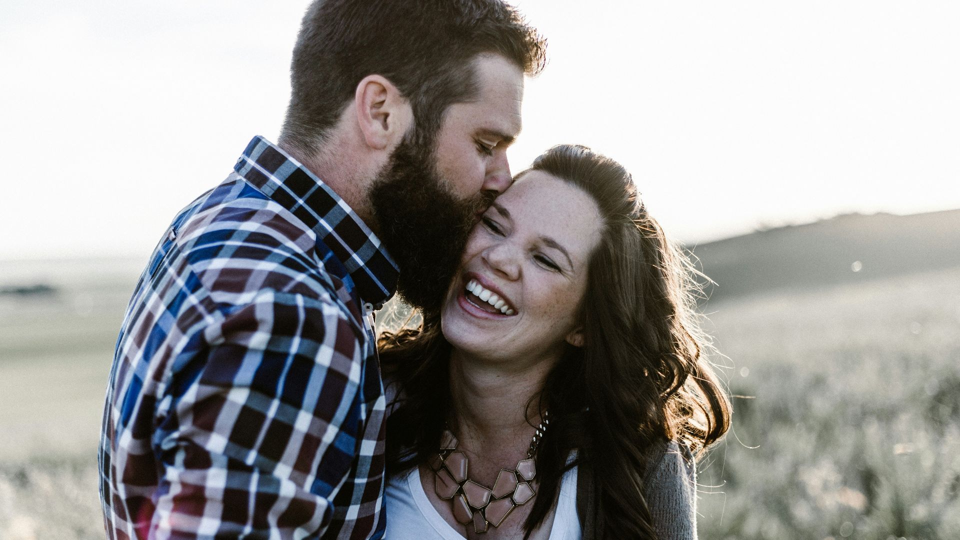 man kissing woman in grass area