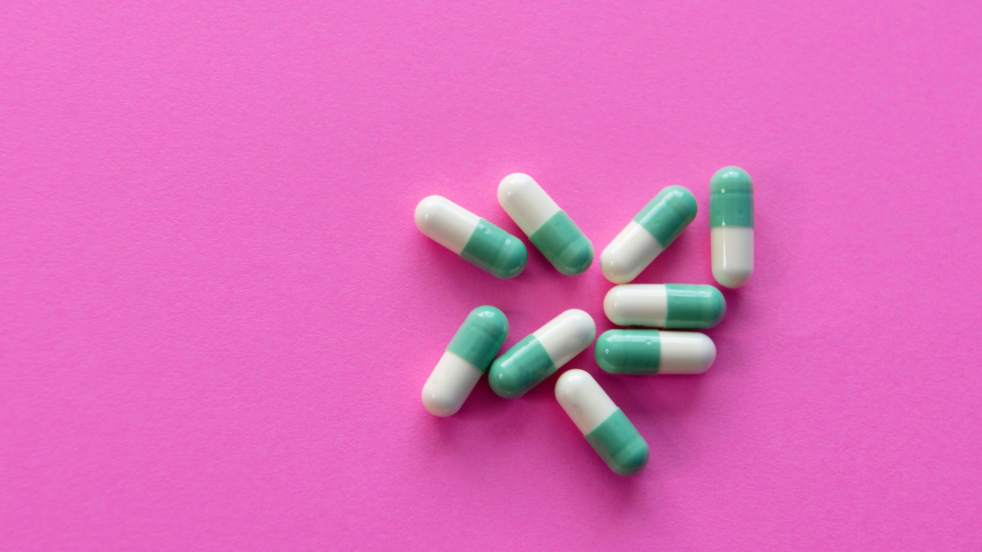 white and blue medication pill on pink textile