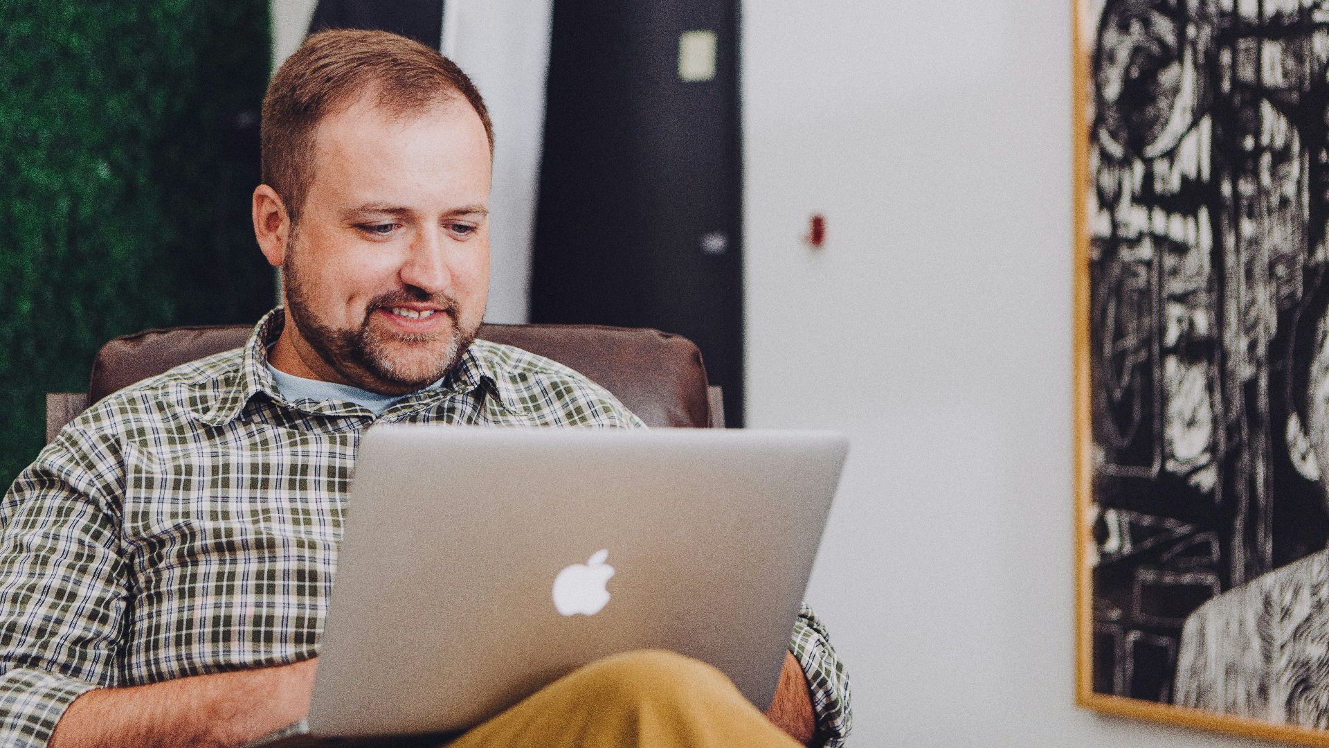 man smiling and using MacBook