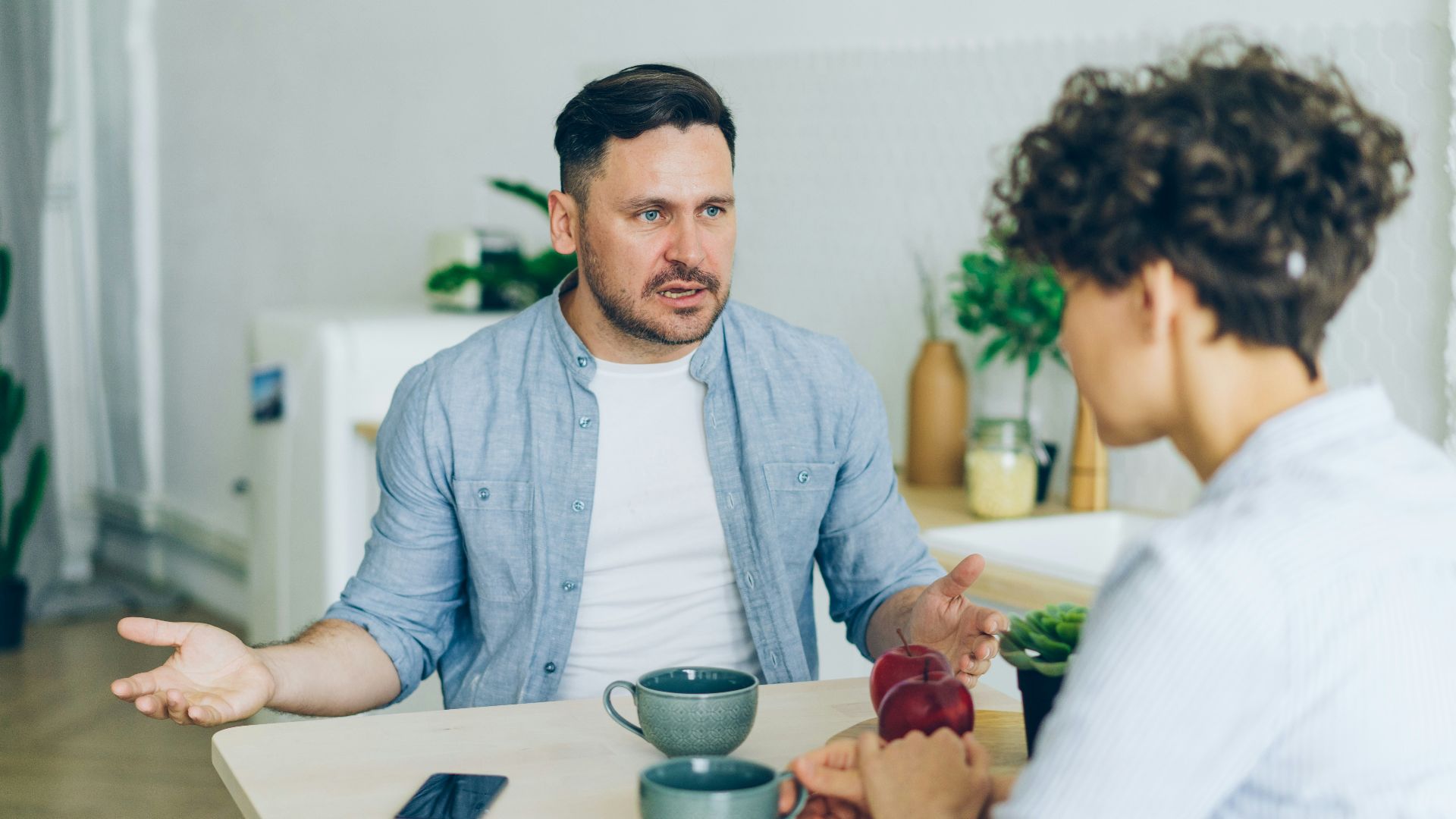 a man sitting at a table talking to a woman