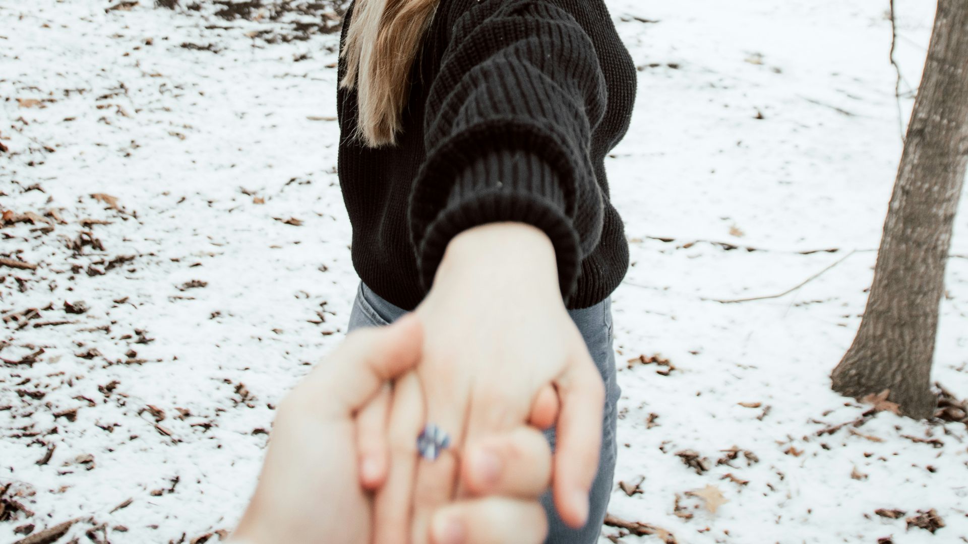 woman in black sweater standing on snow covered ground during daytime