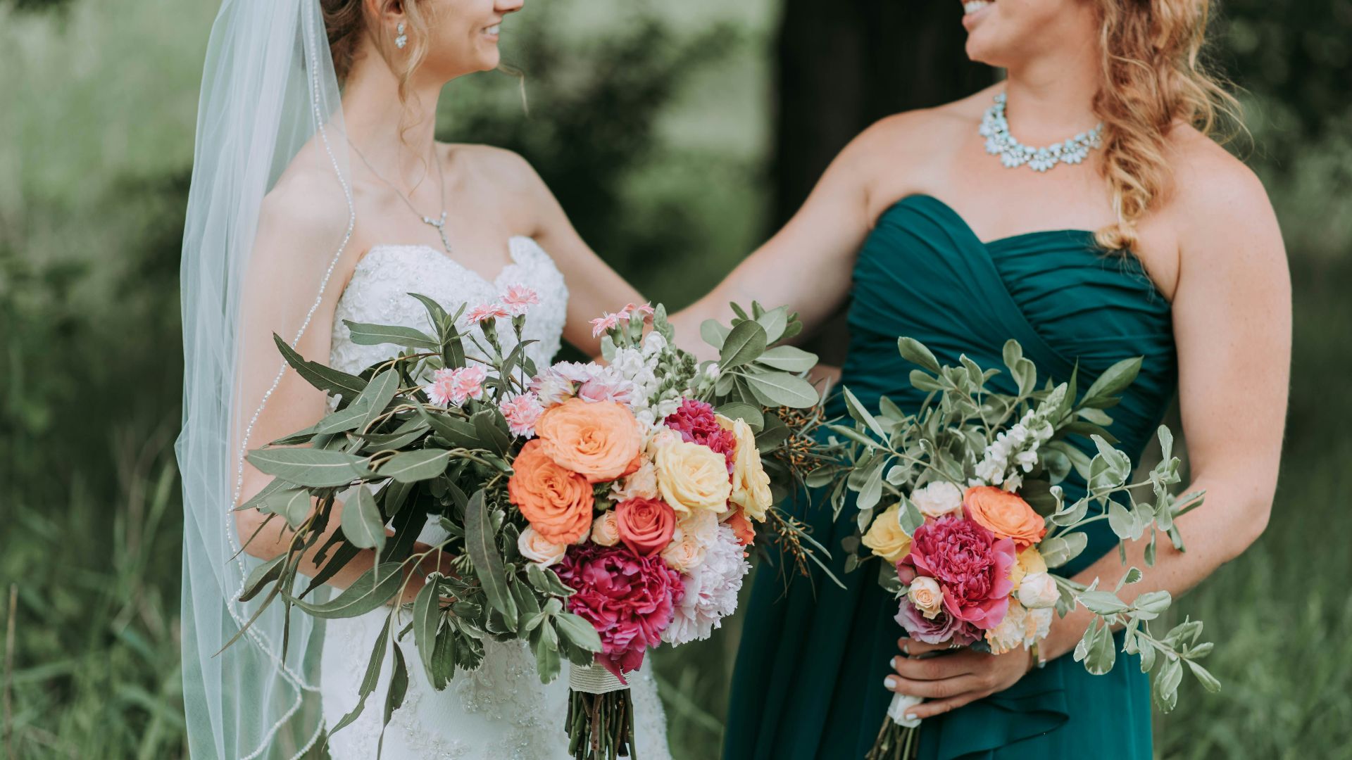 bride holding bouquet of assorted-color flowers standing on grass field