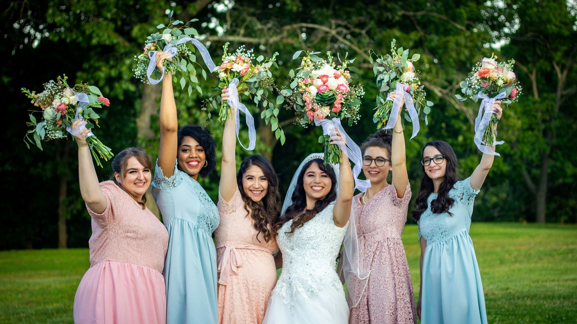 group of women in pink dresses holding bouquet of flowers