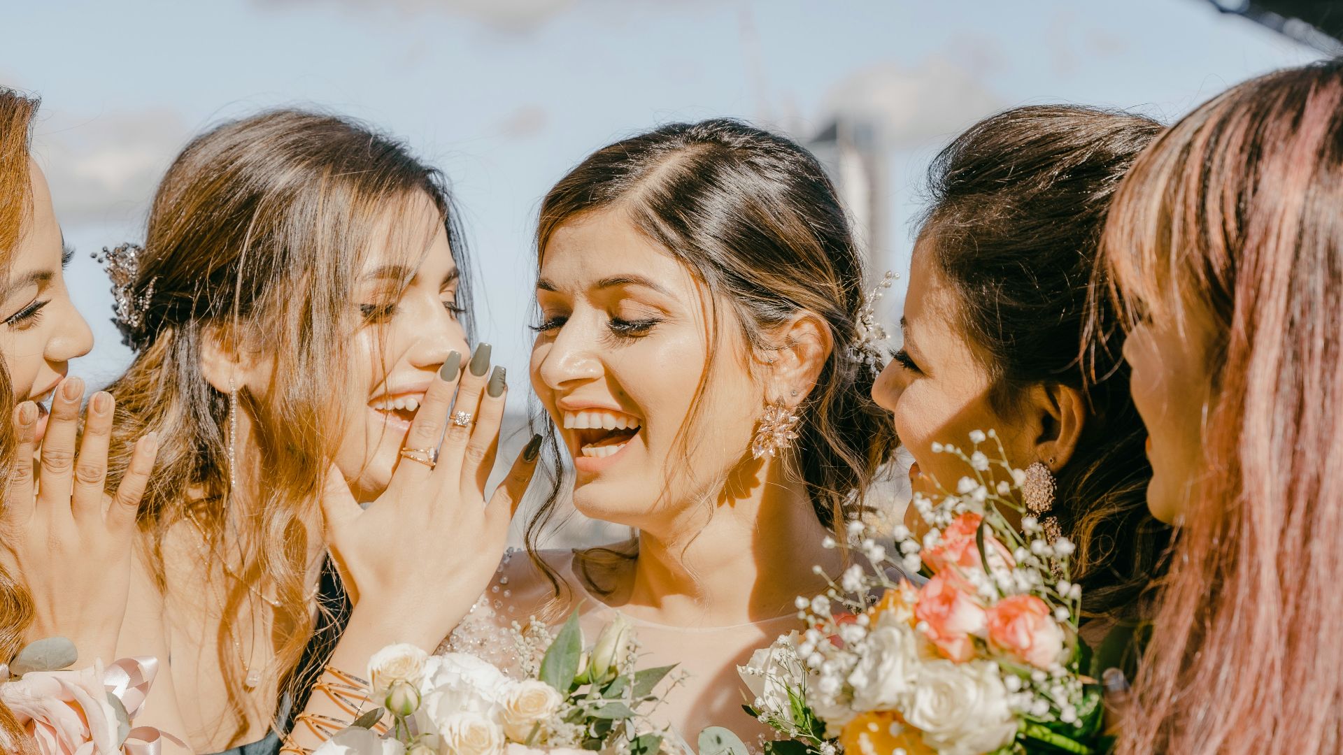 3 women in white floral dress holding bouquet of flowers