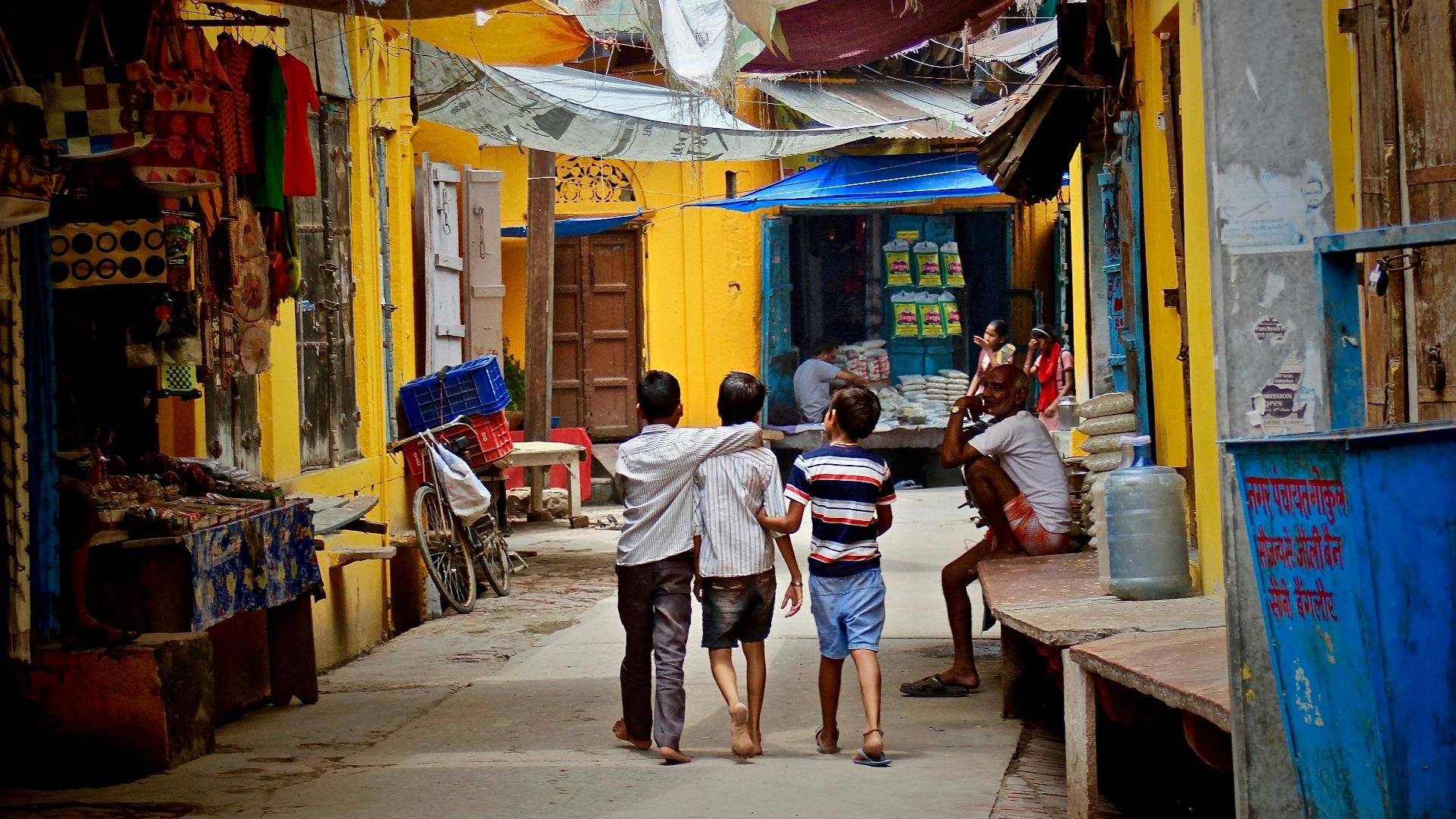three boys walking between buildings at daytime