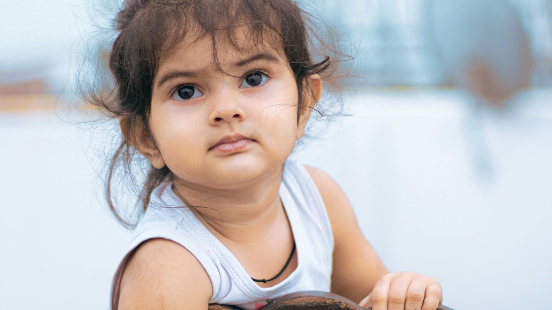 girl in white tank top sitting on brown wooden chair
