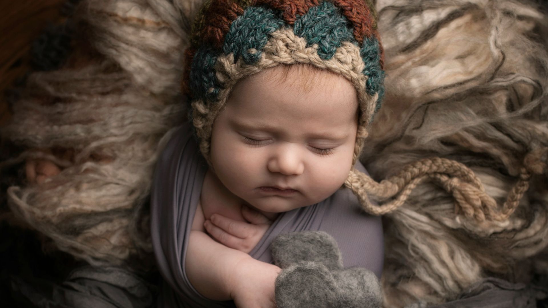 girl in grey long sleeve shirt lying on grey fur textile