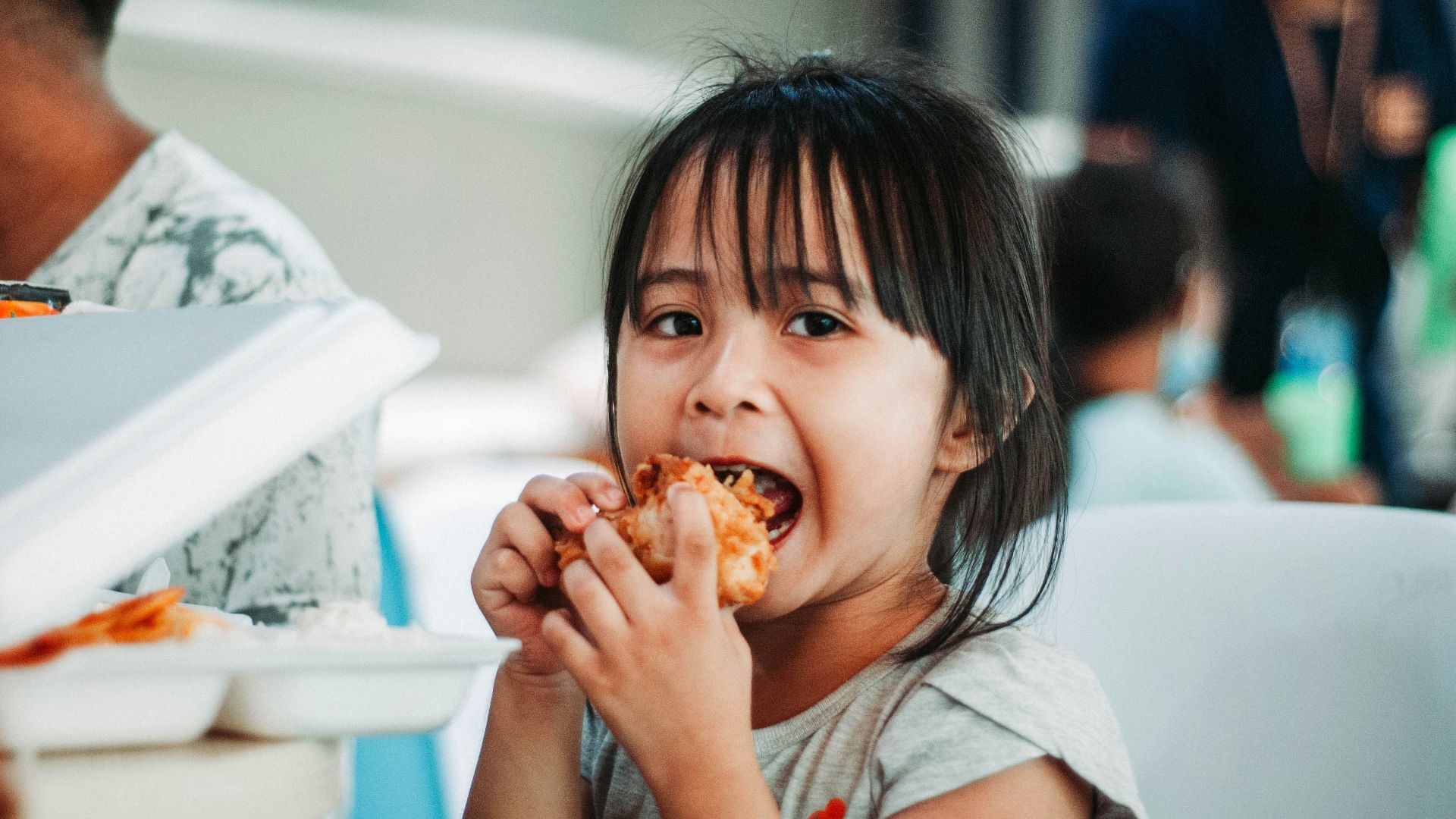 girl biting a good by table at daytime