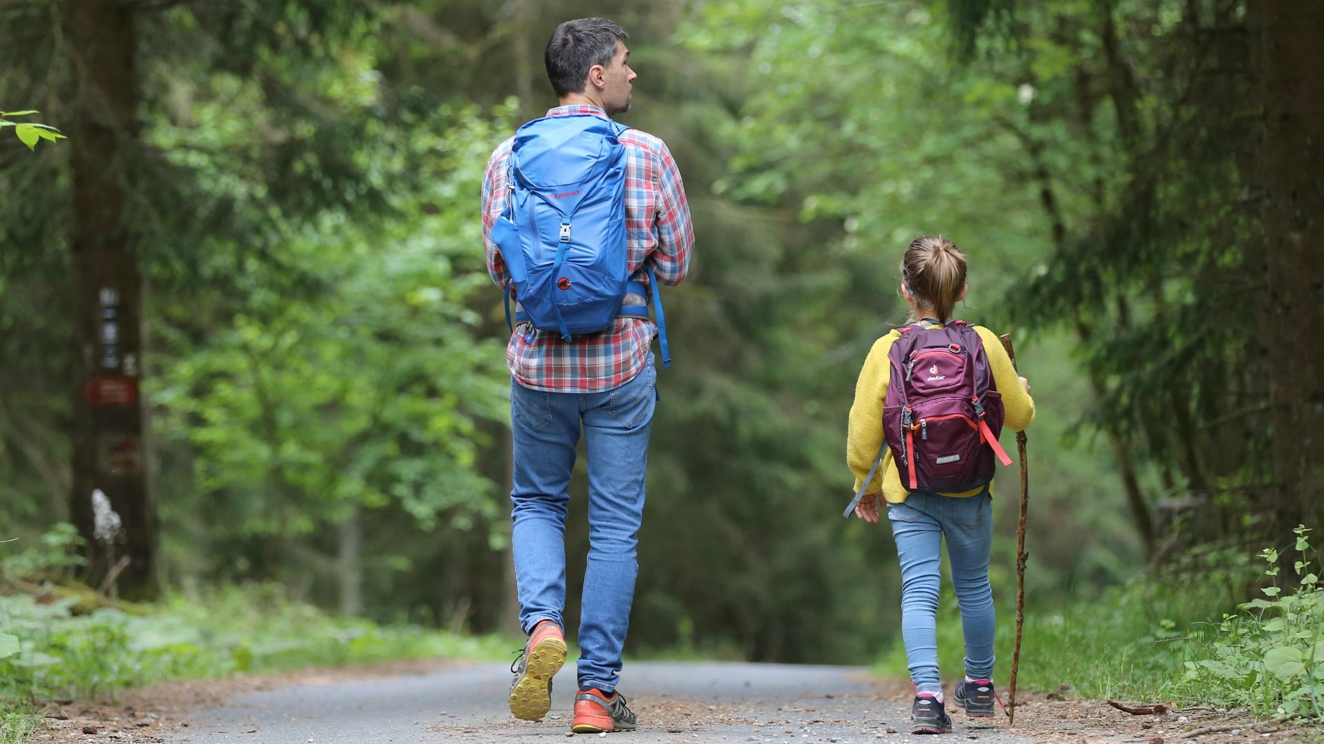 man in blue jacket and blue denim jeans walking on dirt road during daytime