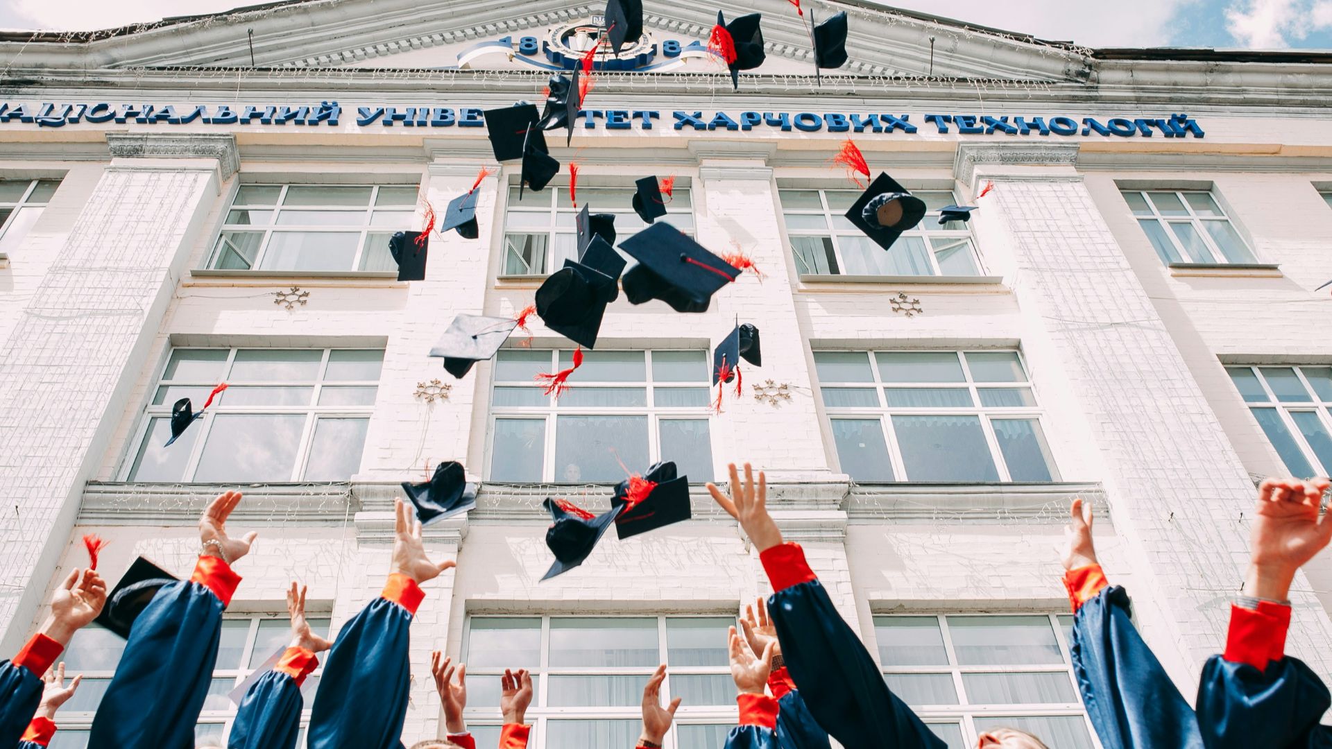 group of fresh graduates students throwing their academic hat in the air
