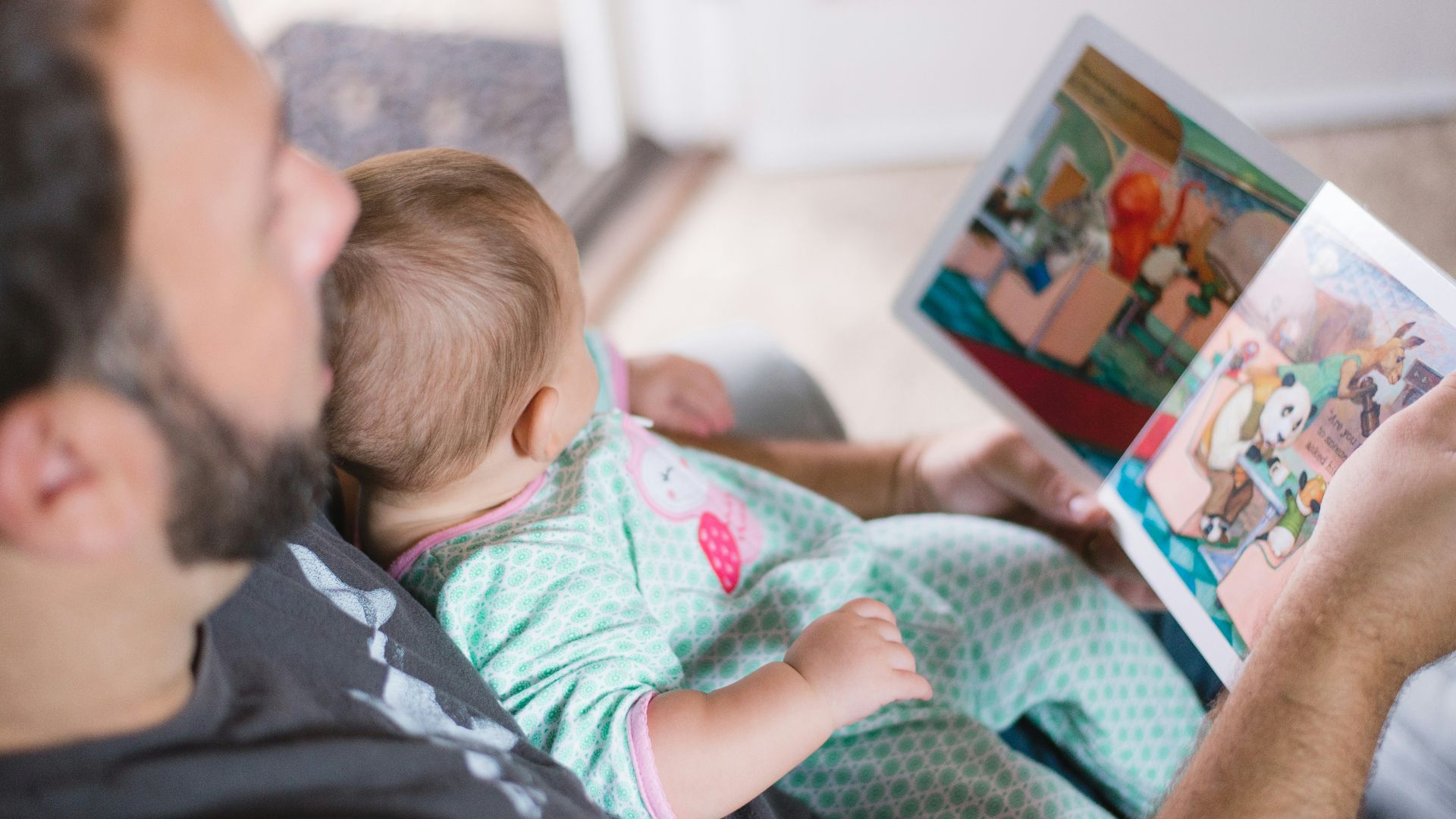 person carrying baby while reading book