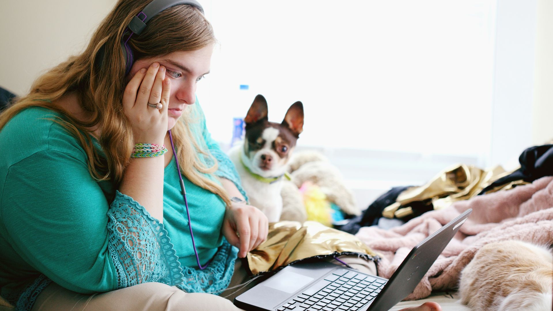 woman in teal long sleeve shirt holding black laptop computer