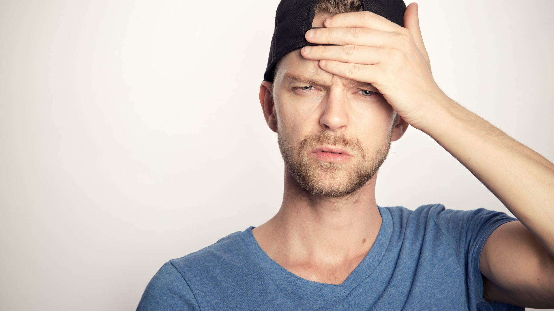 man in blue crew neck shirt covering his face