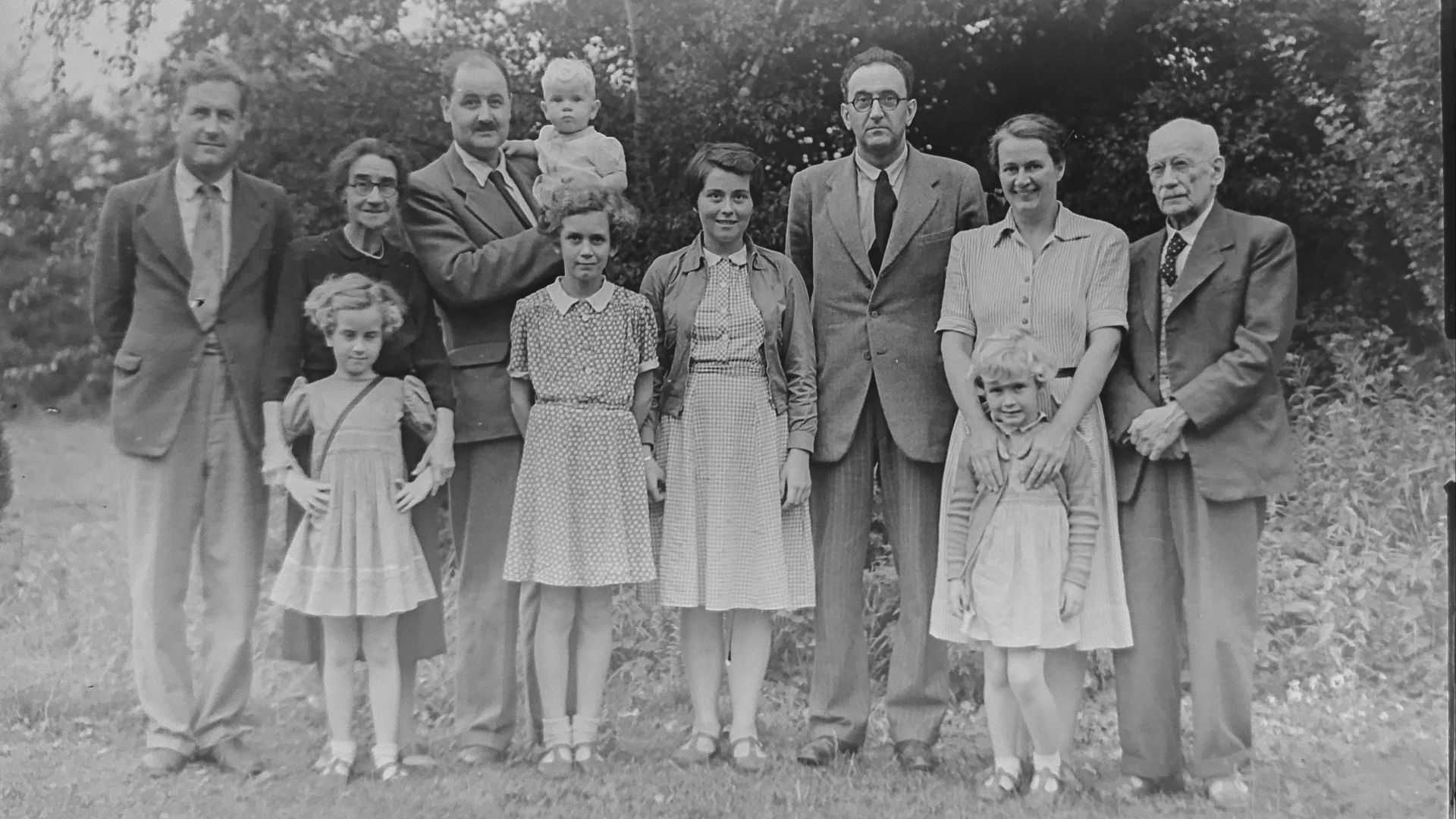 grayscale photo of family standing near trees