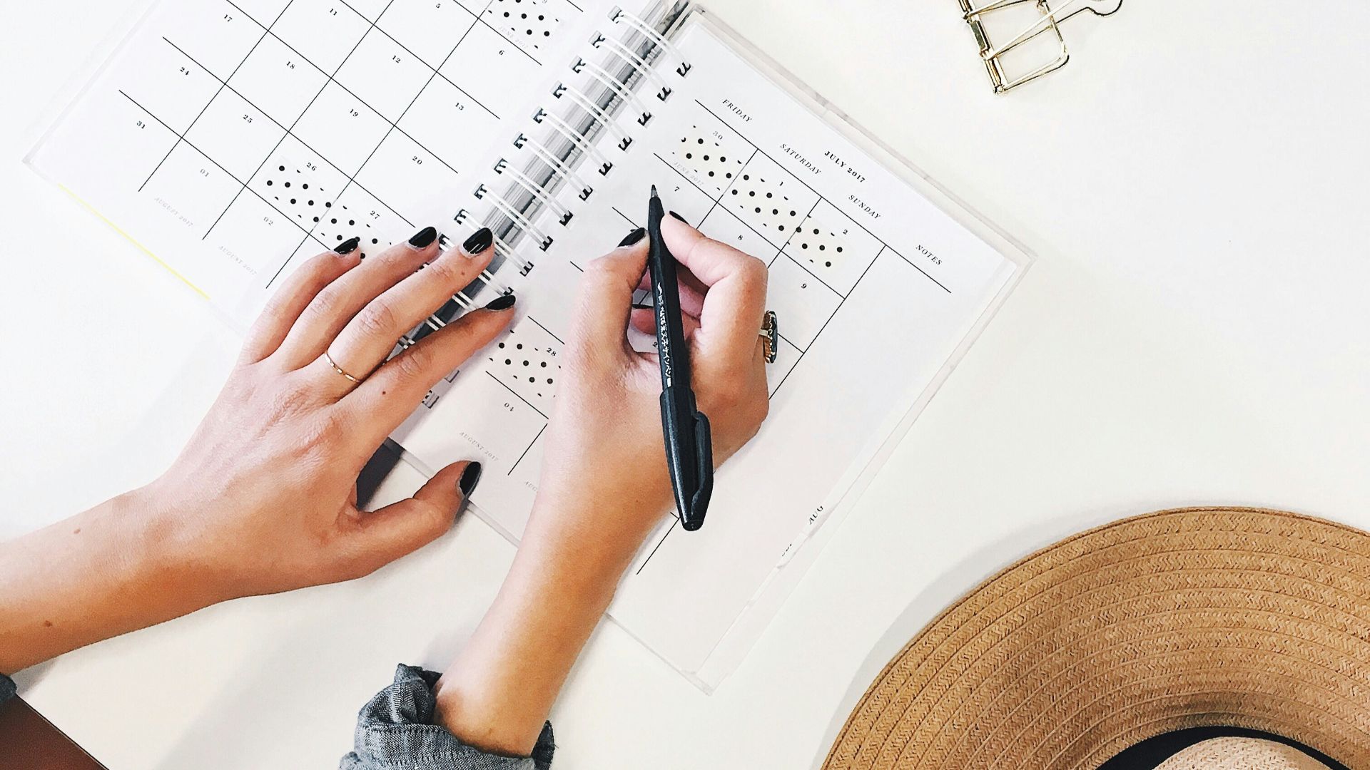 person holding ballpoint pen writing on white paper