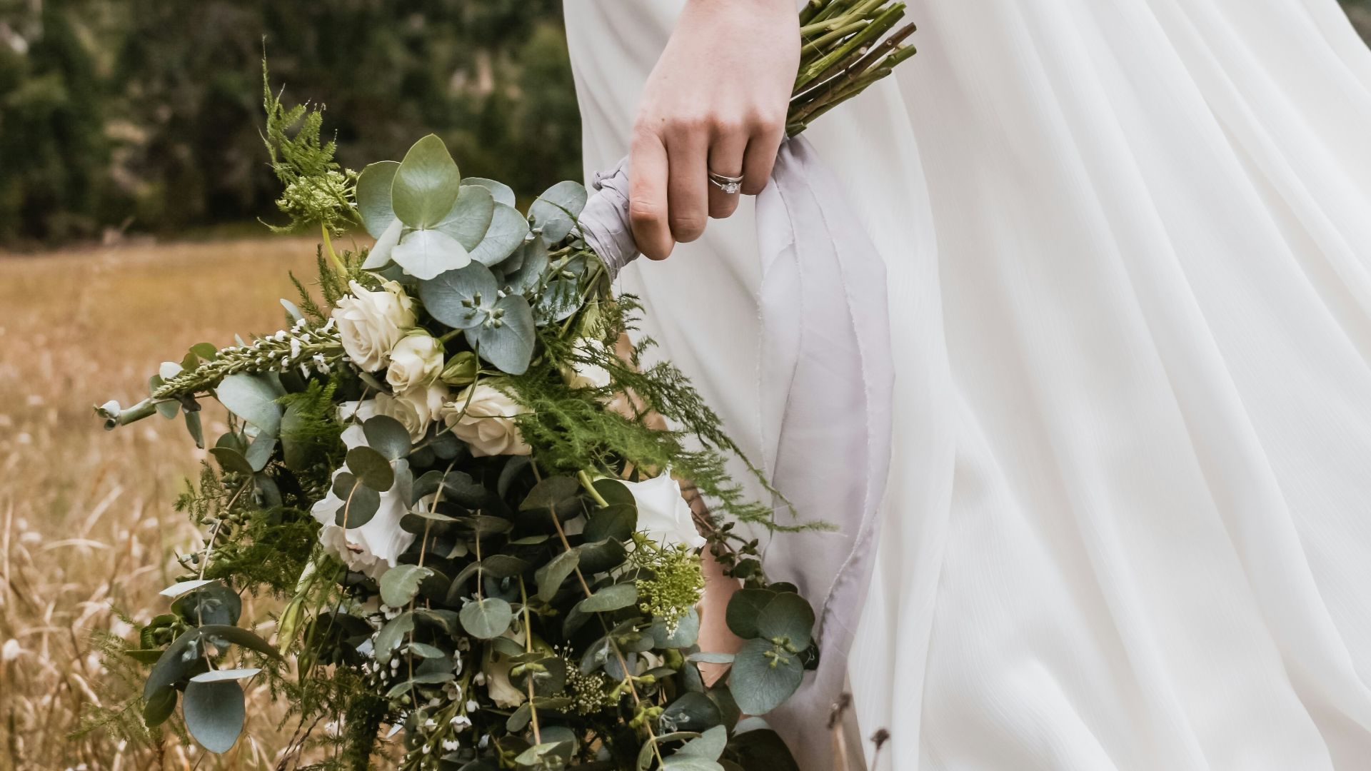 woman in white wedding dress with bouquet of flowers in hand