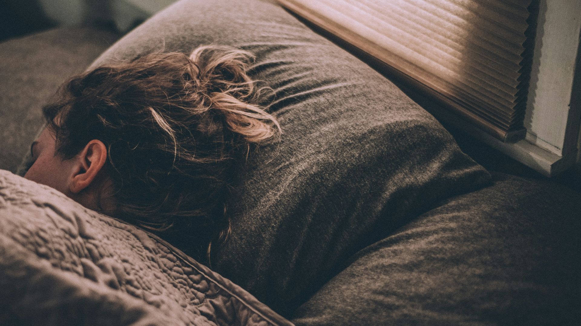 woman sleeping on bed under blankets