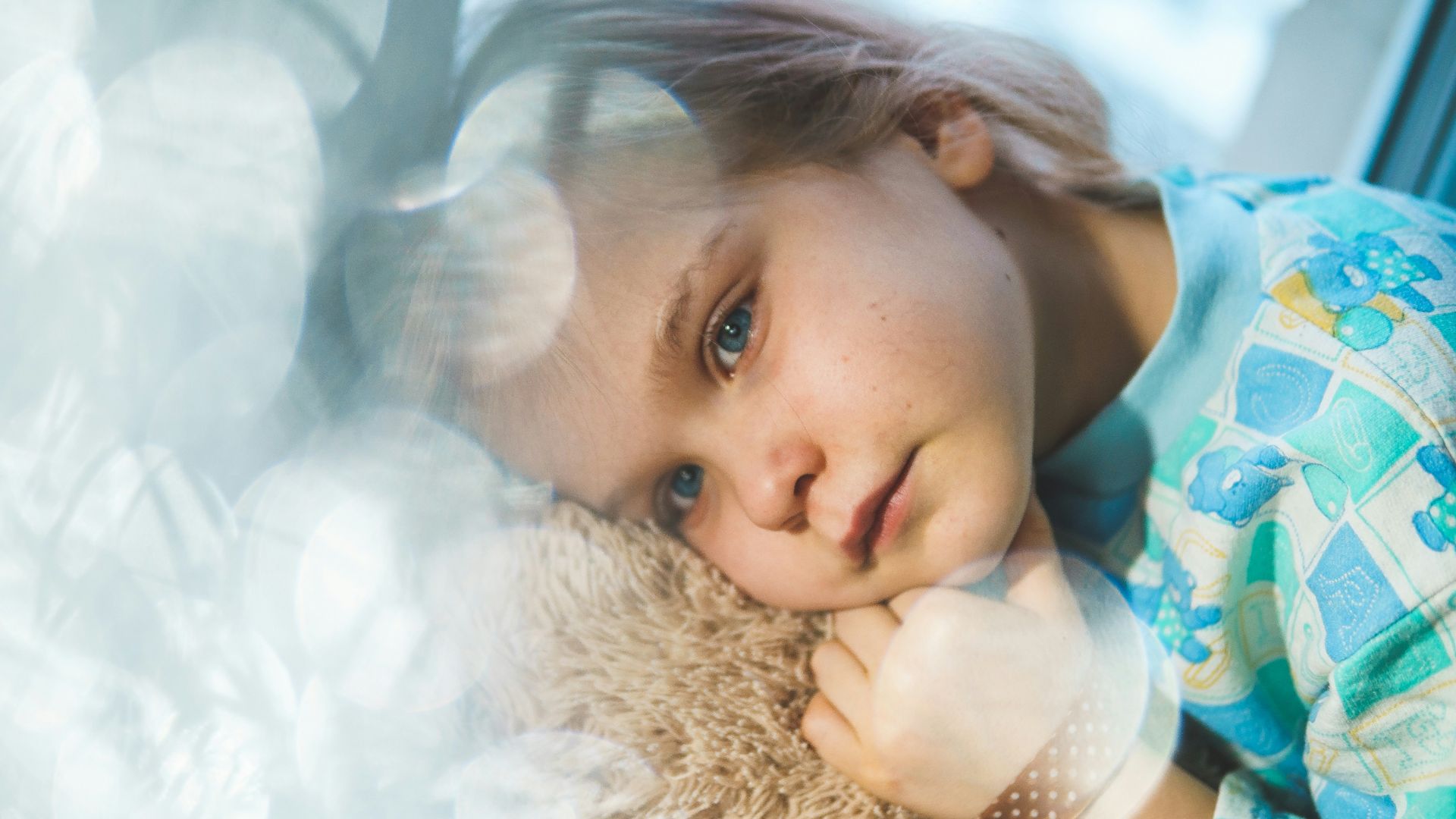 girl in white and blue floral dress lying on white fur textile
