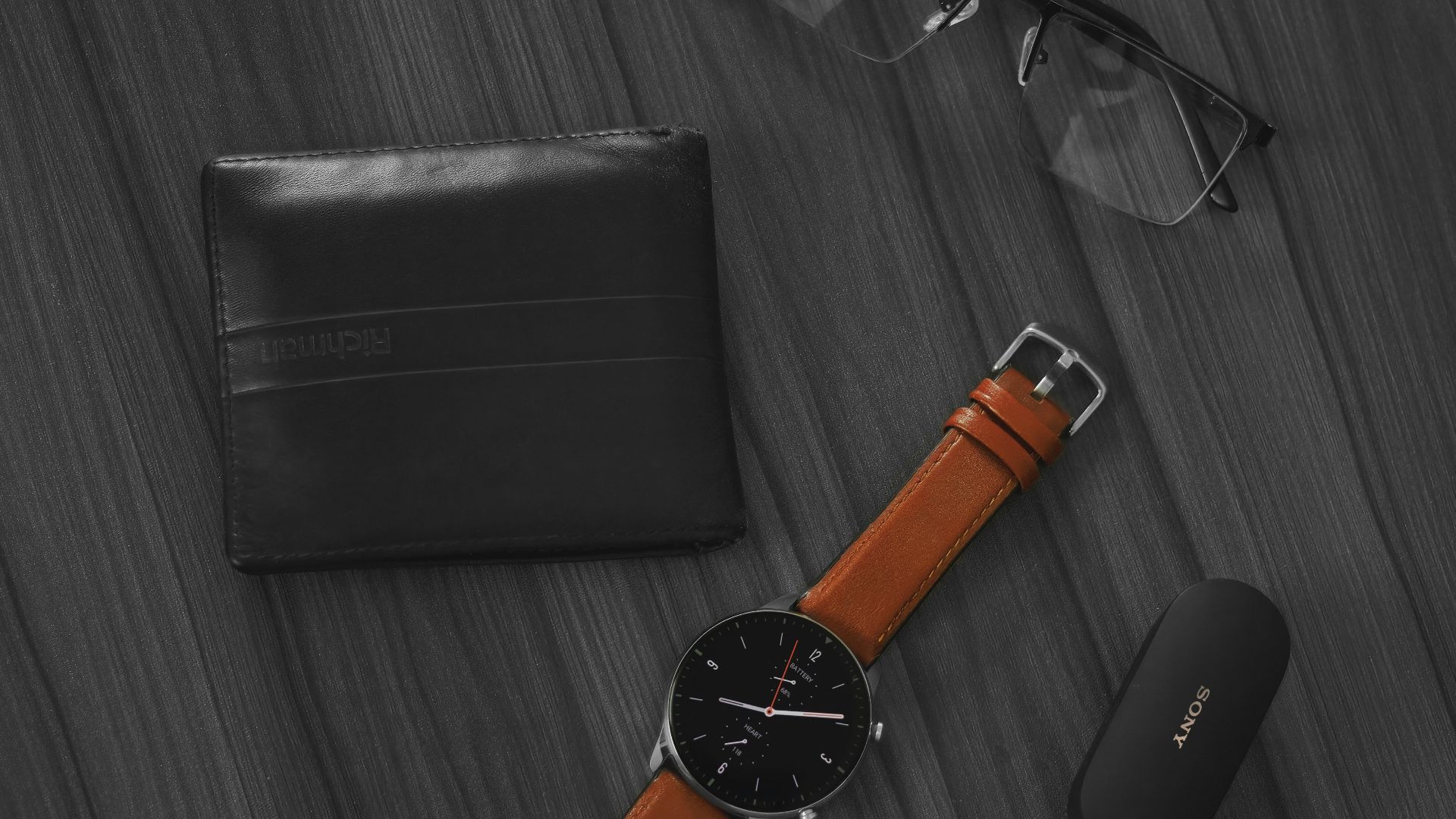 a pair of glasses, a watch, and a wallet on a table