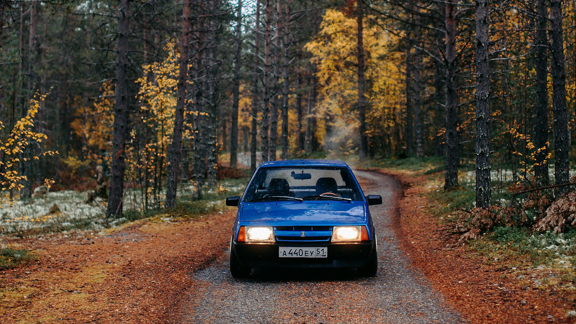 black car on dirt road in between trees during daytime