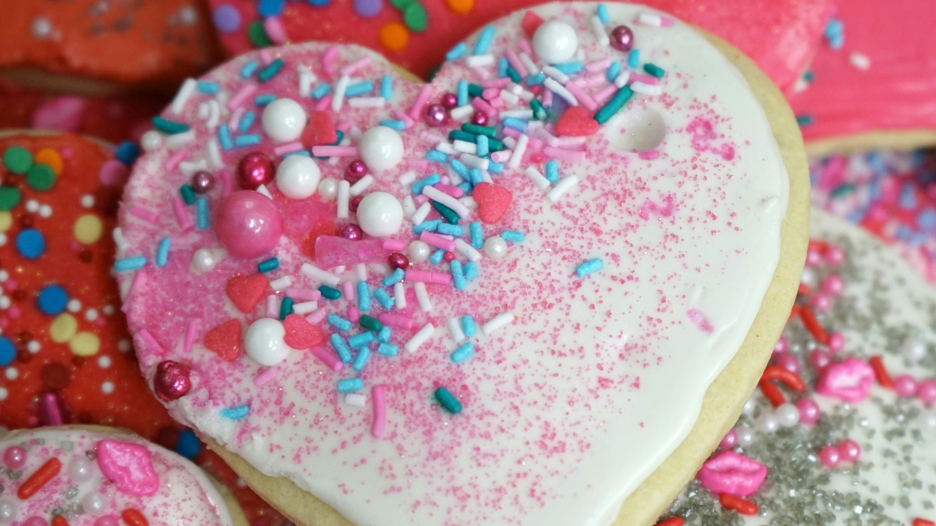 a pile of heart shaped cookies with sprinkles
