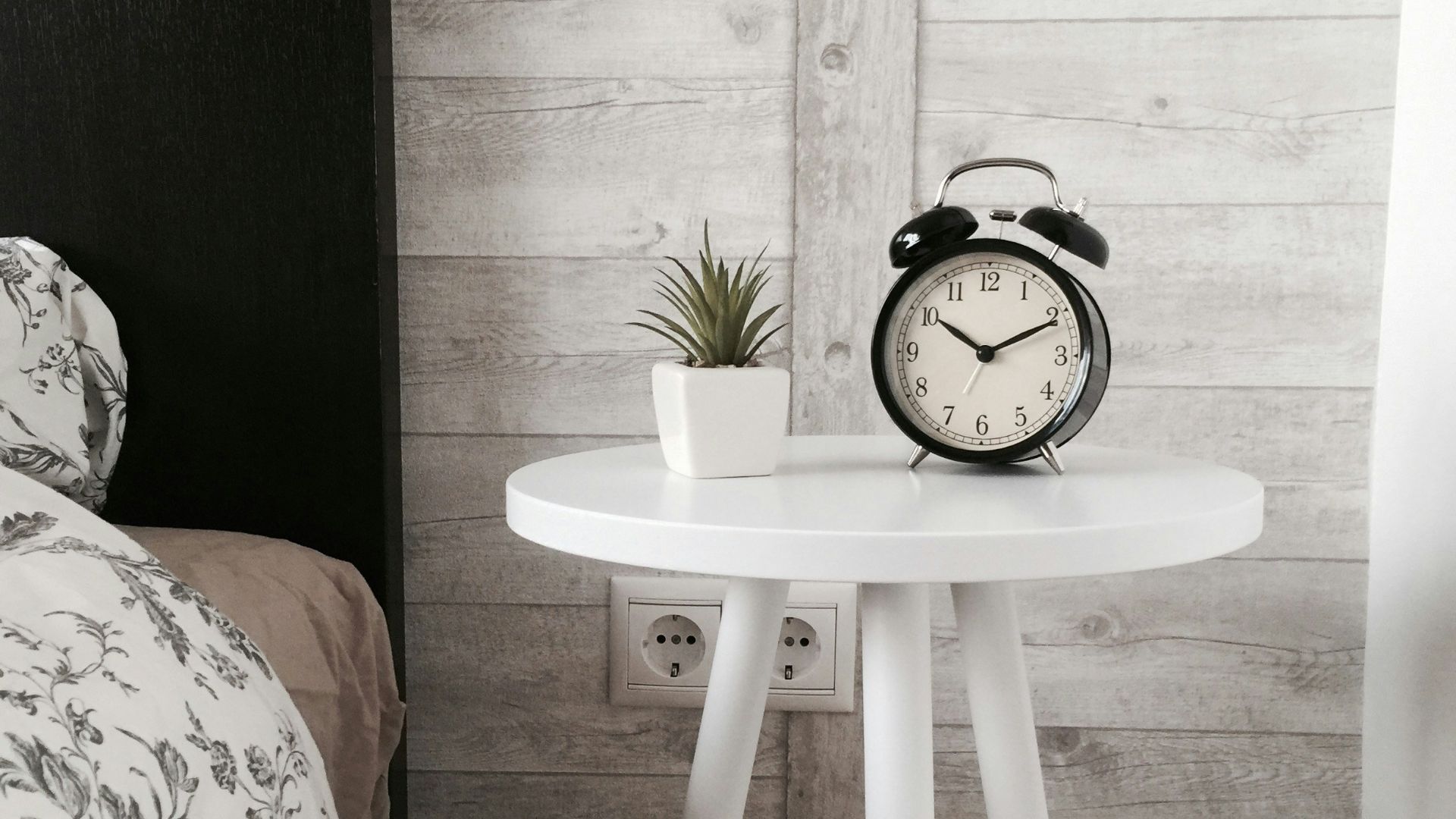 black alarm clock at 10:10 on white wooden table near table