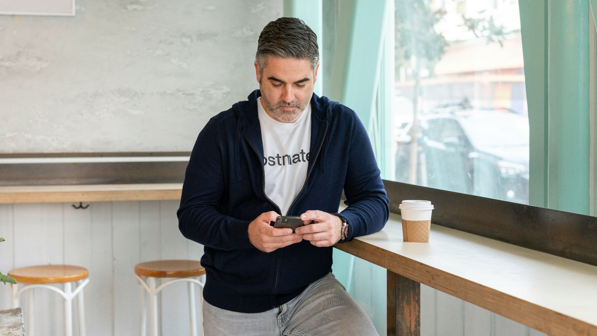 man in blue long sleeve shirt and gray pants holding black smartphone