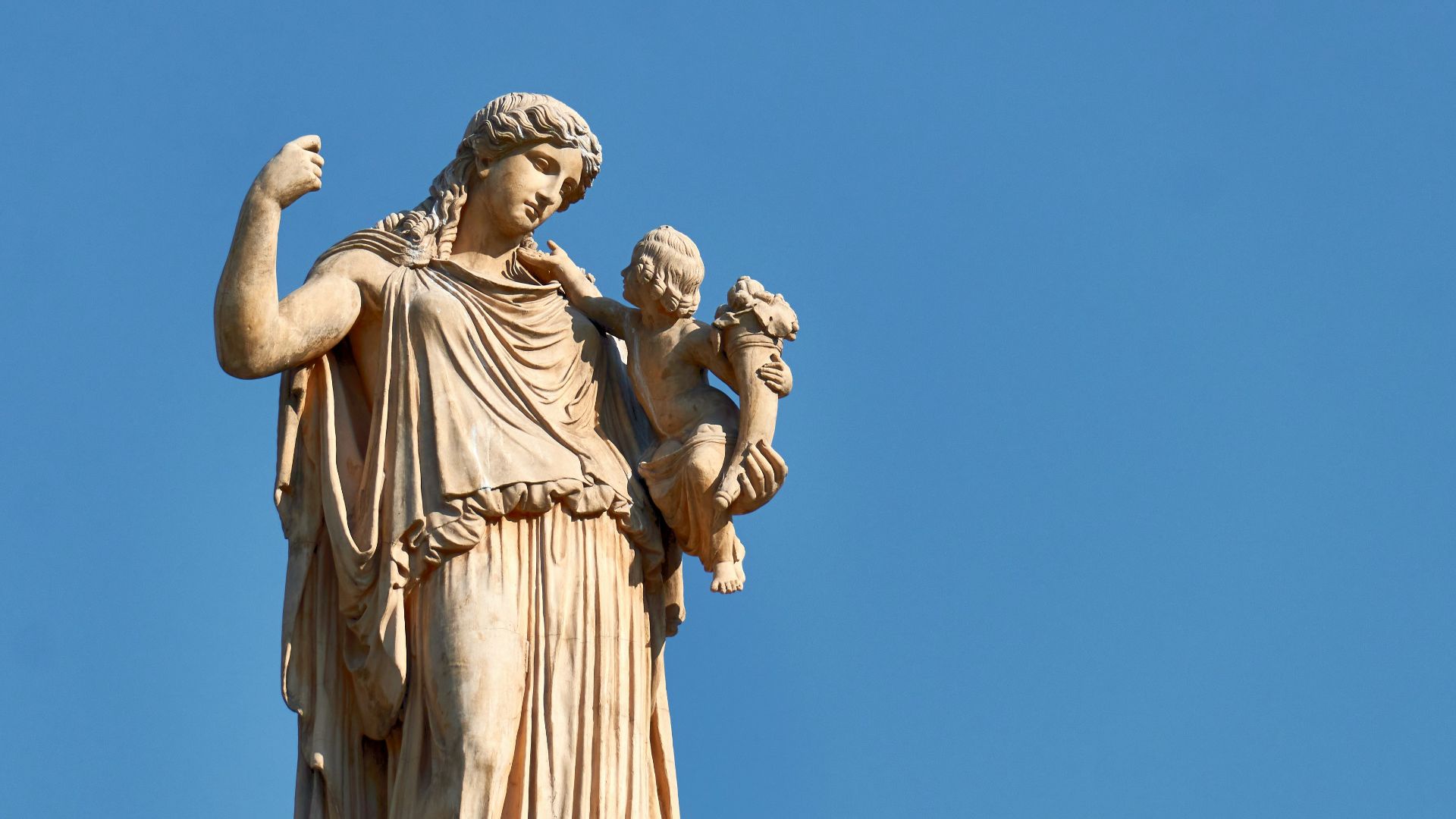 a statue of a woman holding a child on top of a building