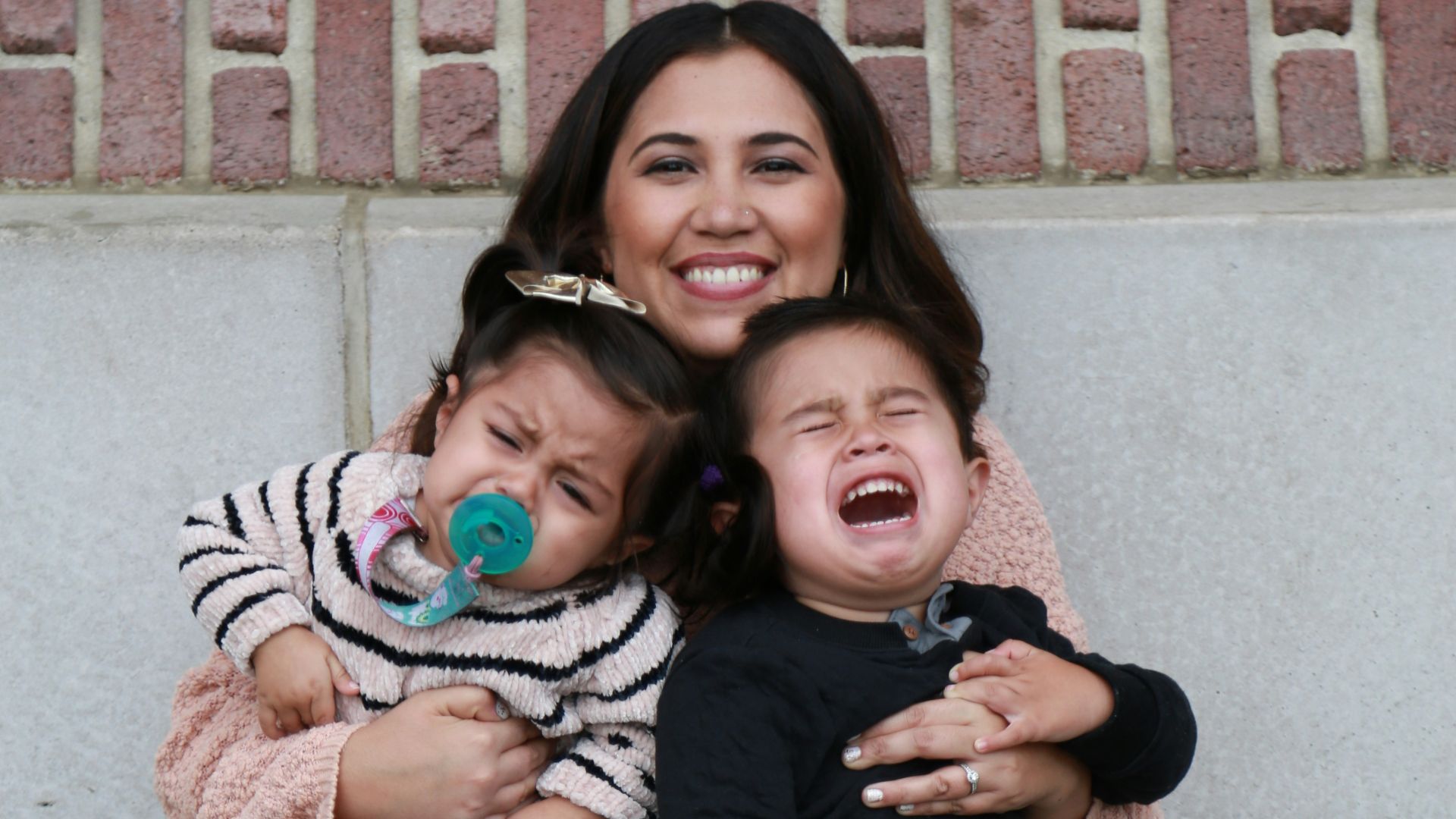 woman in black long sleeve shirt carrying girl in pink jacket
