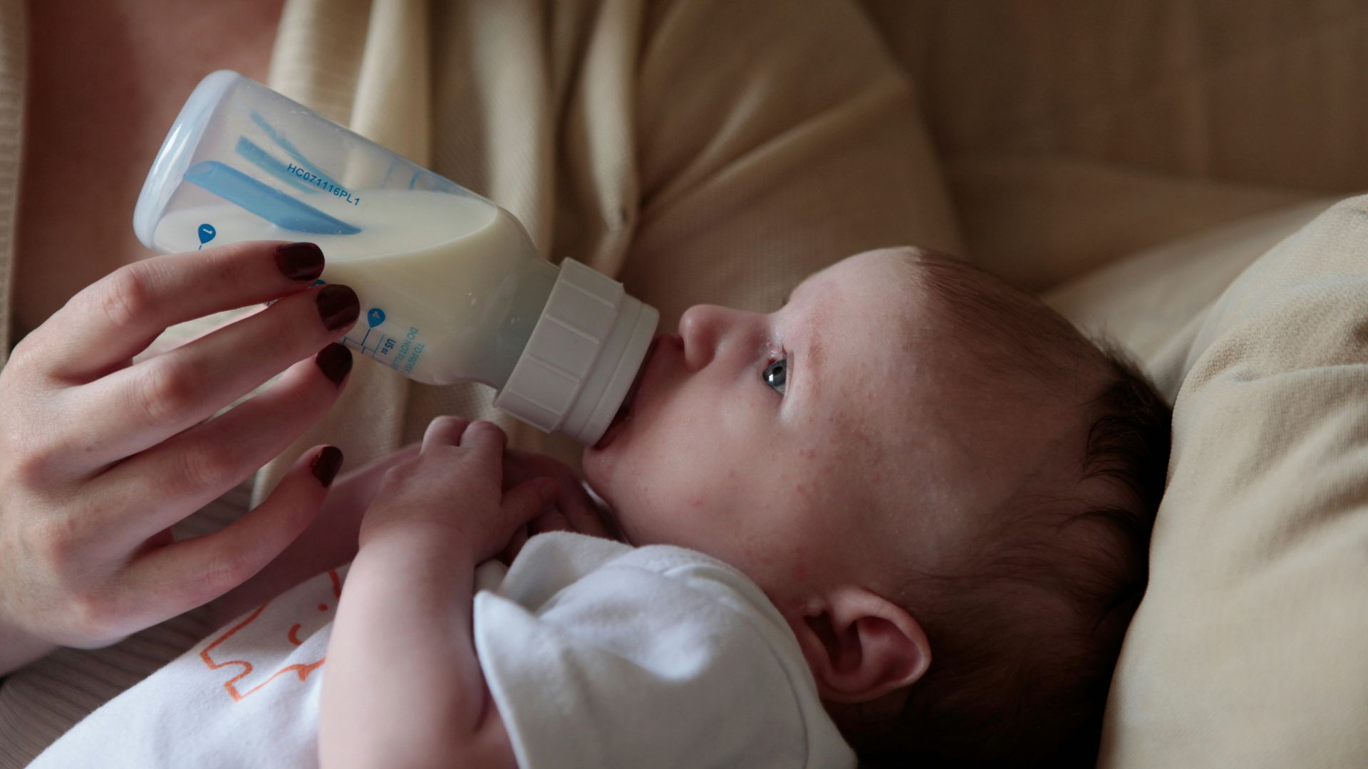 a woman feeding a baby with a bottle of milk