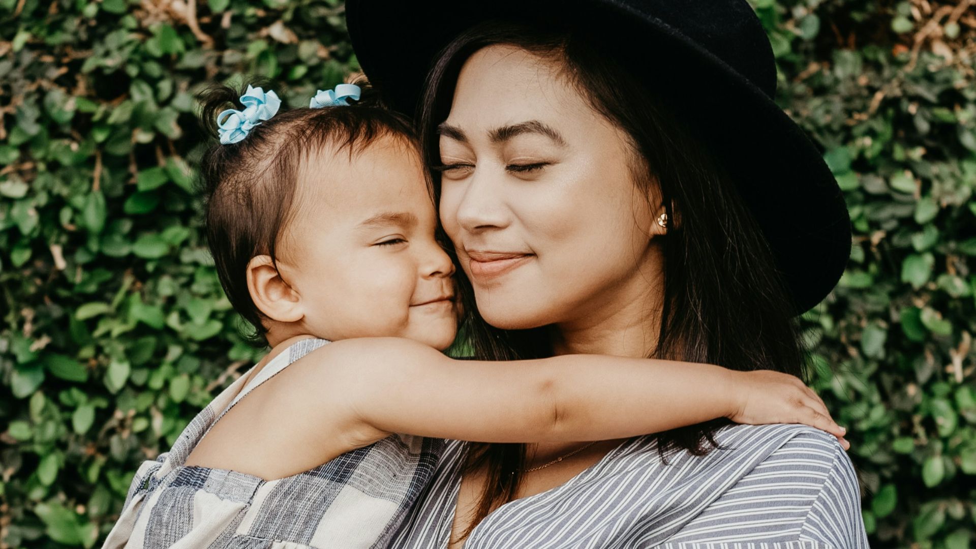 woman carrying child beside hedges
