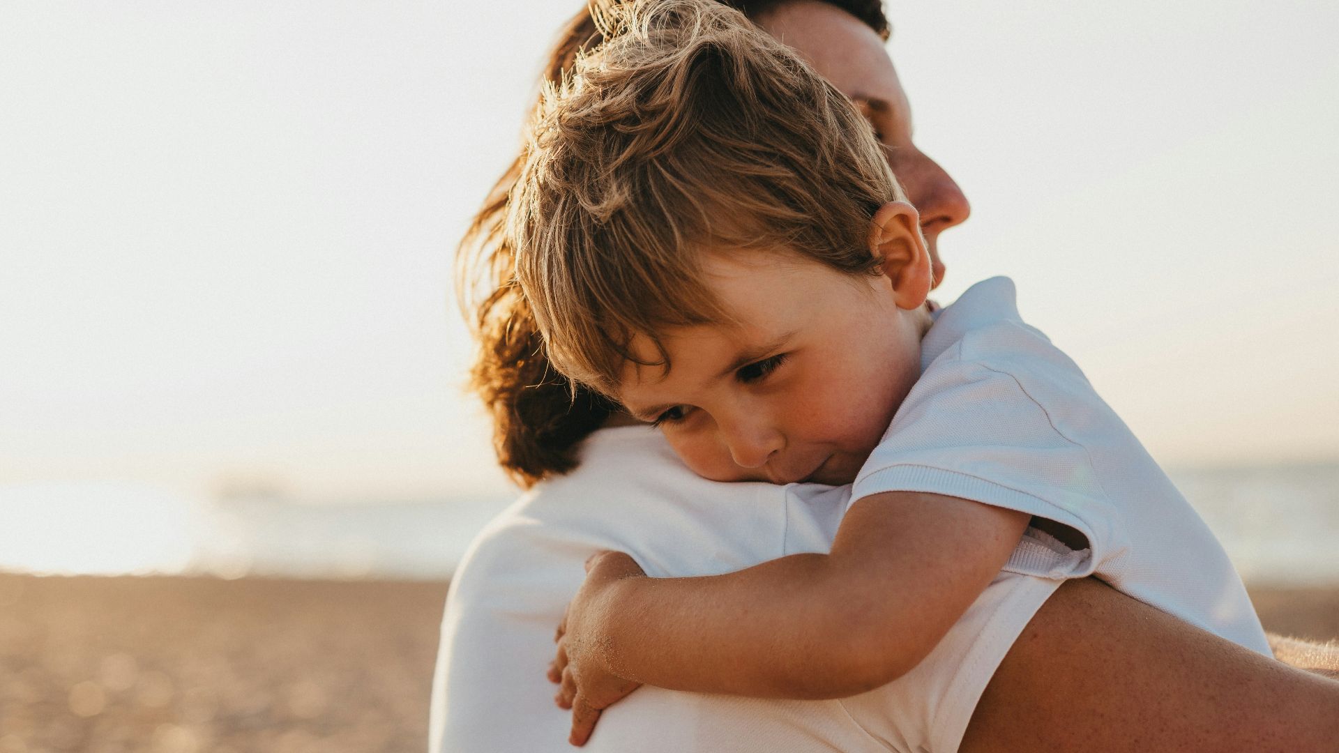 boy hugging woman during daytime