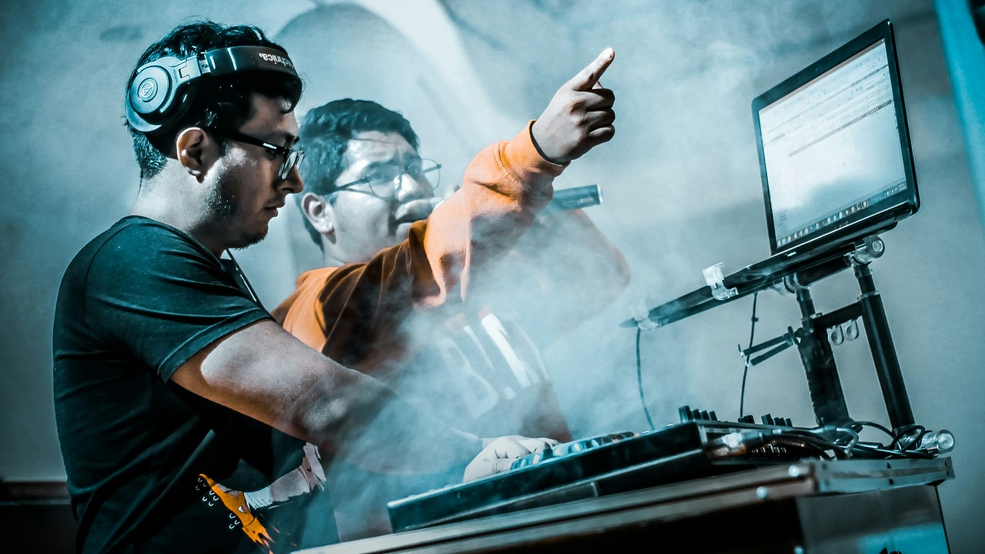 man controlling DJ controller beside man with microphone
