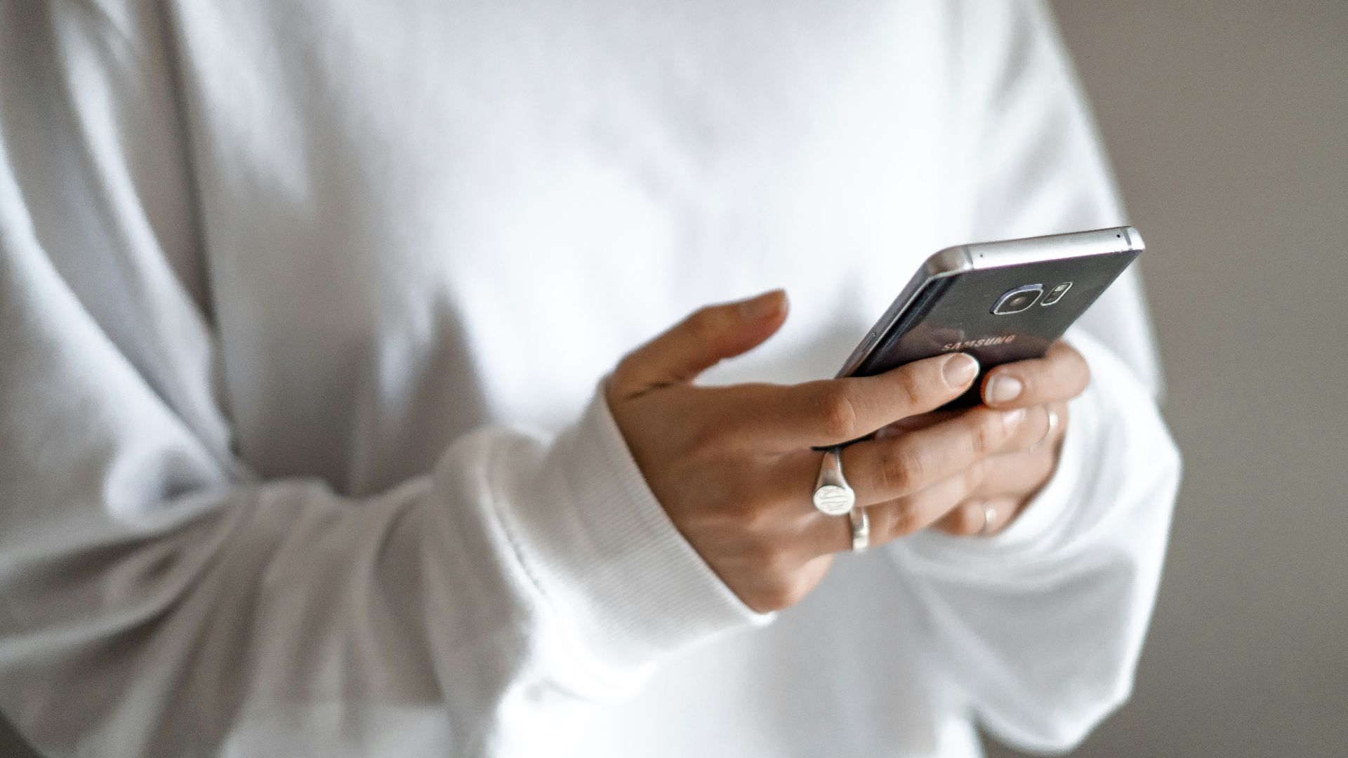 person in white long sleeve shirt holding black smartphone