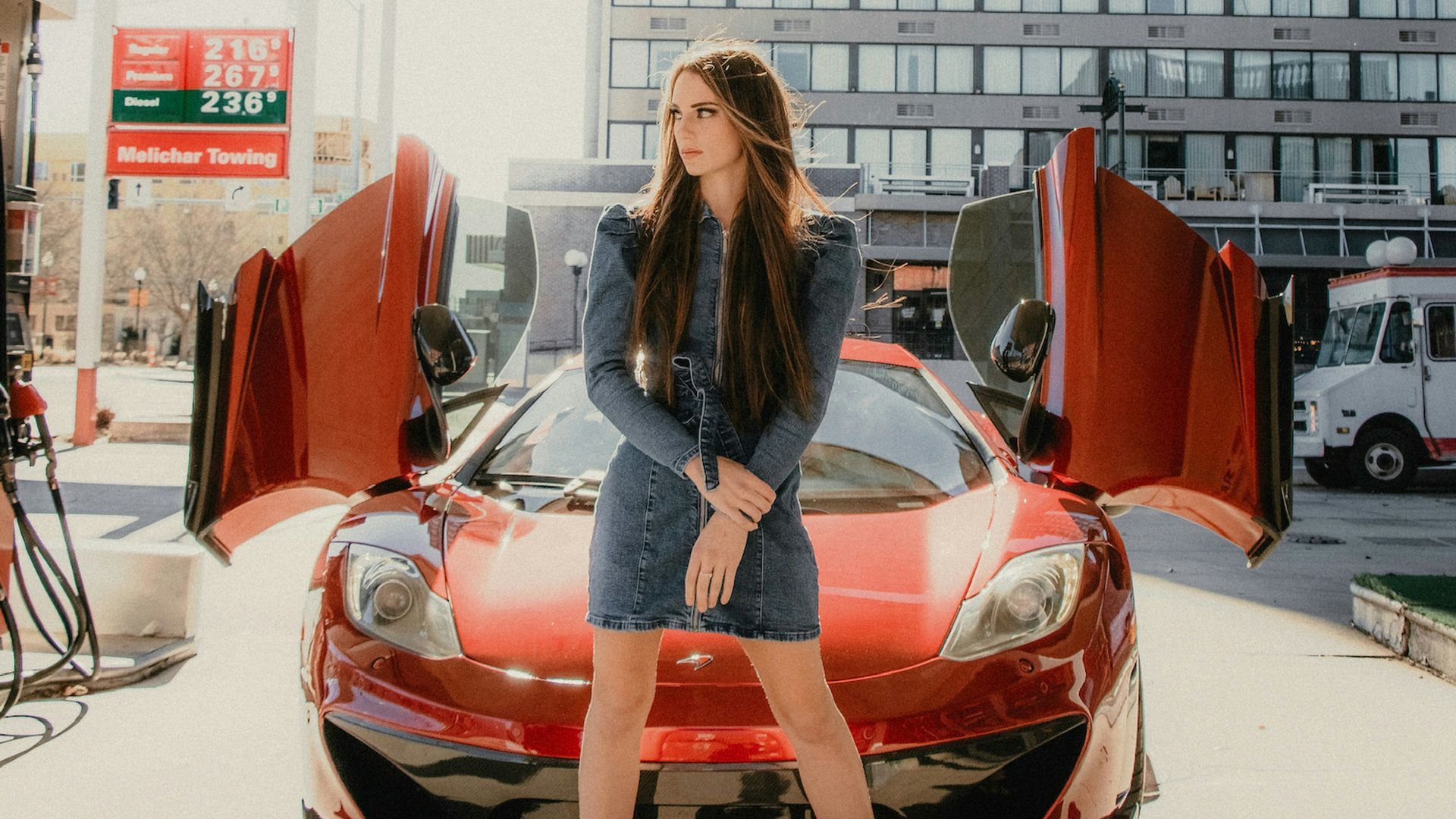 woman in black long sleeve shirt and blue denim jeans standing beside red ferrari car