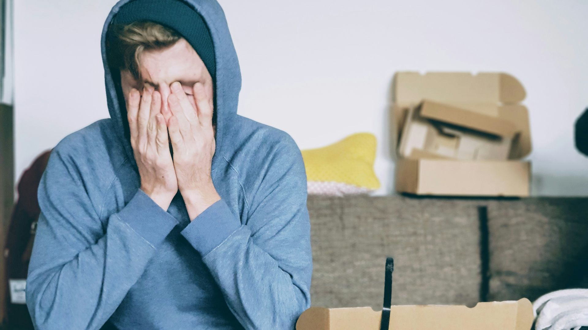 man covering face with both hands while sitting on bench